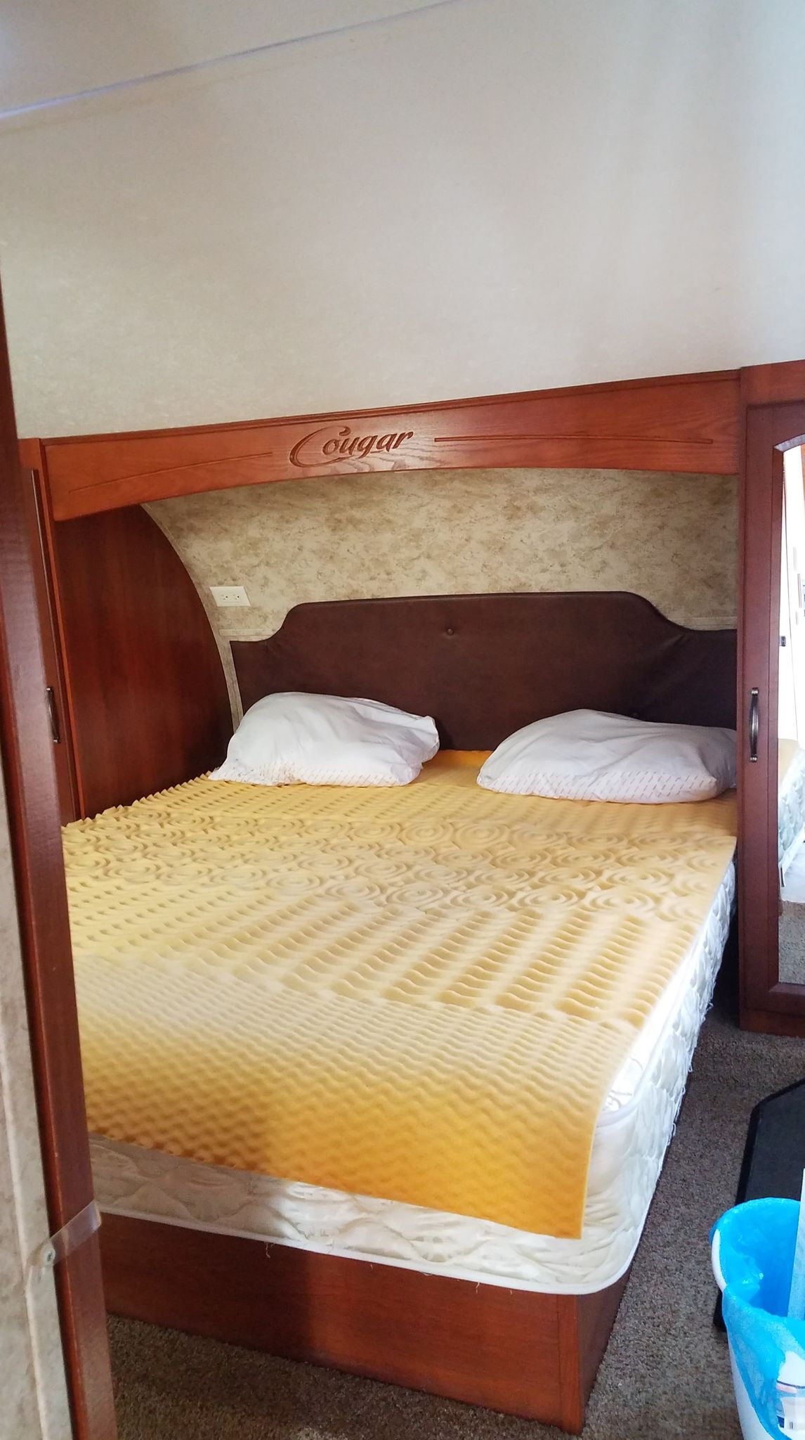 Cougar RV rental bedroom with a bed, yellow foam topper, pillows, and warm wooden interior.. Keystone Cougar Xlite 2012