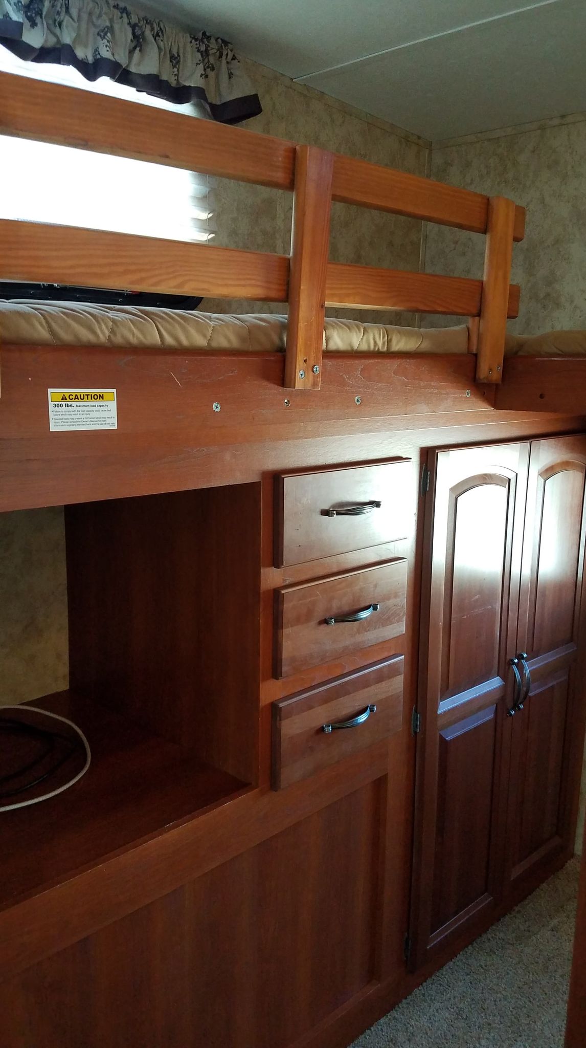 RV rental bunk bed setup: wooden frame, safety railing, mattress, and integrated storage with drawers and cabinets.. Keystone Cougar Xlite 2012