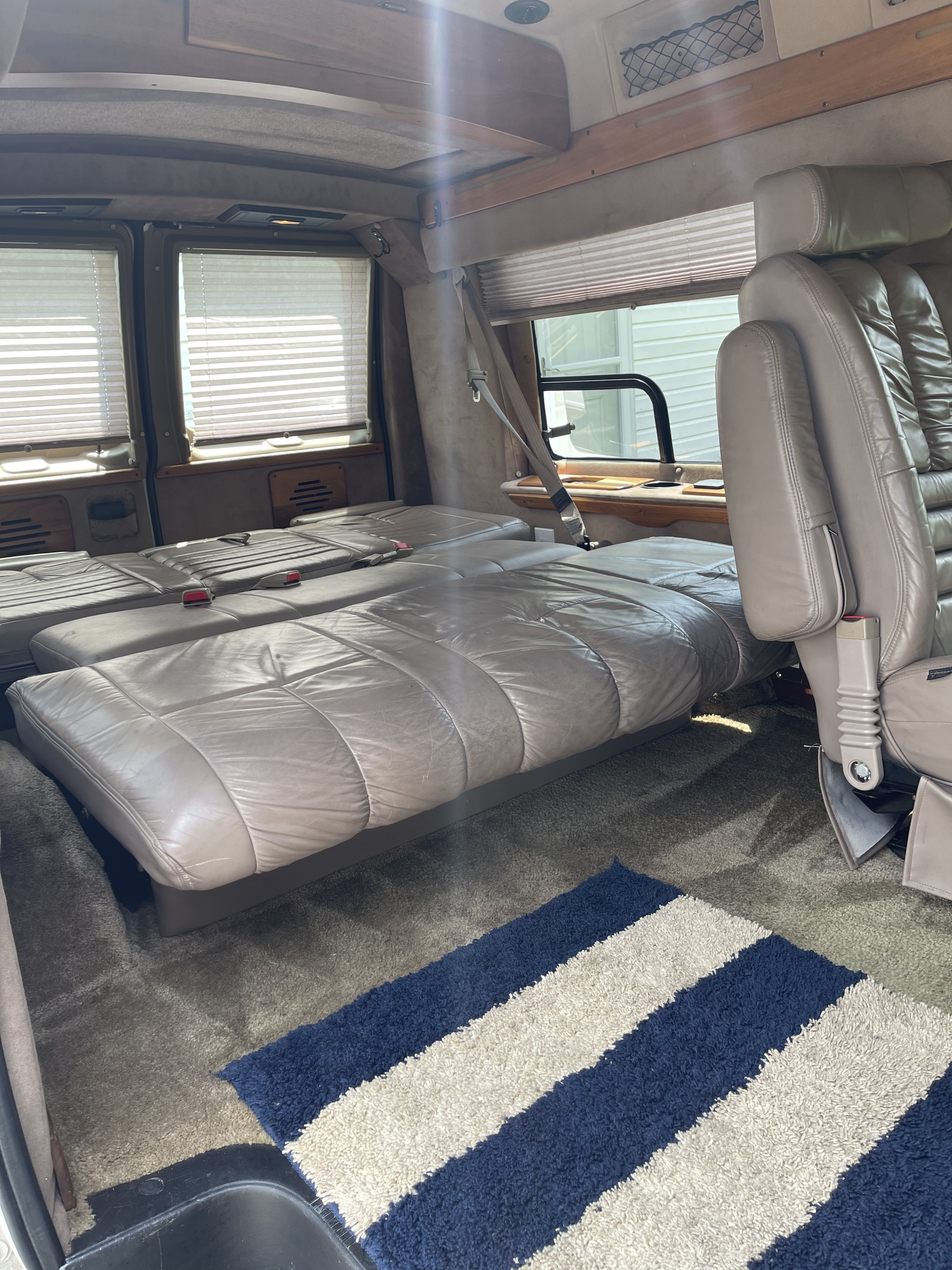 Inside this RV rental, plush leather seats fold into a bed, offering comfort with window blinds and carpeting.. Coachmen Van Conversion 2001