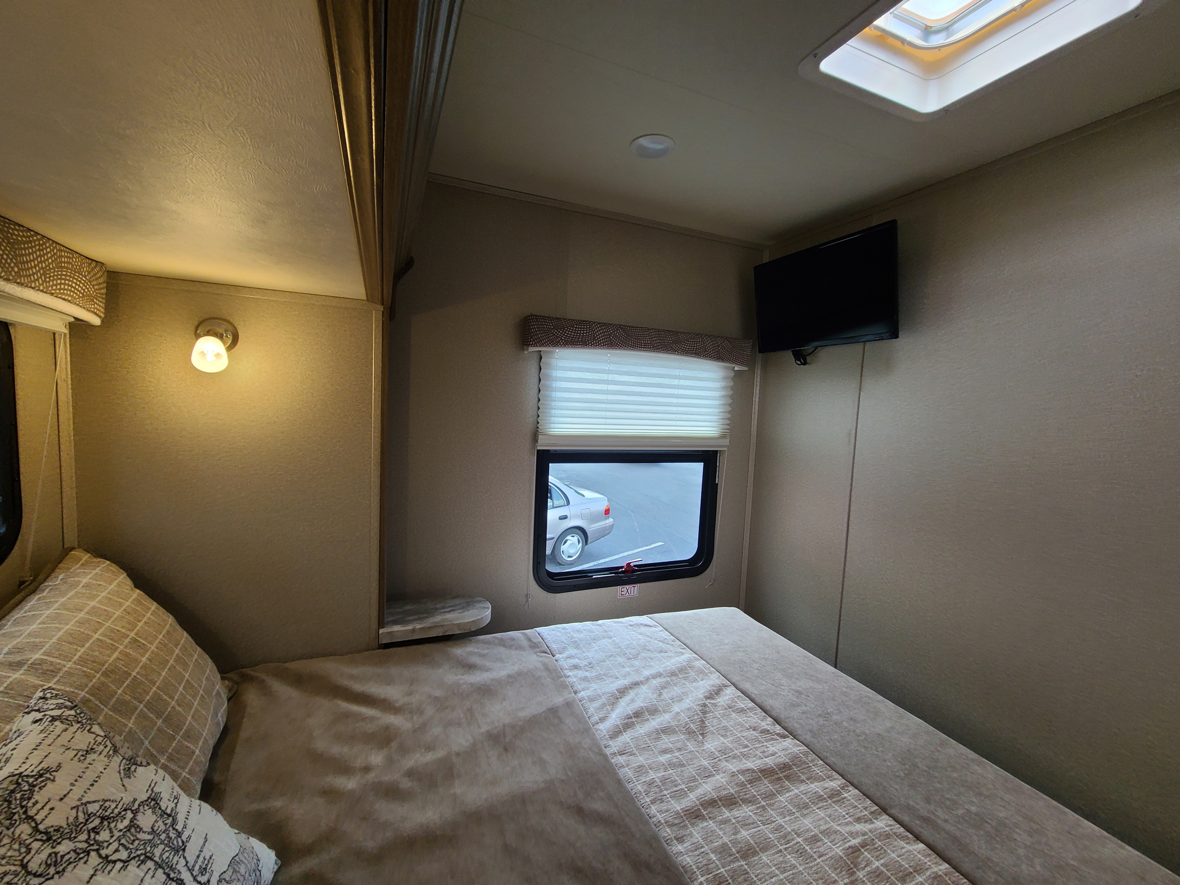 Cozy RV rental bedroom with a comfy bed, window looking out, TV, and skylight. Ready for your adventure.. Odyssey Entegra 2019