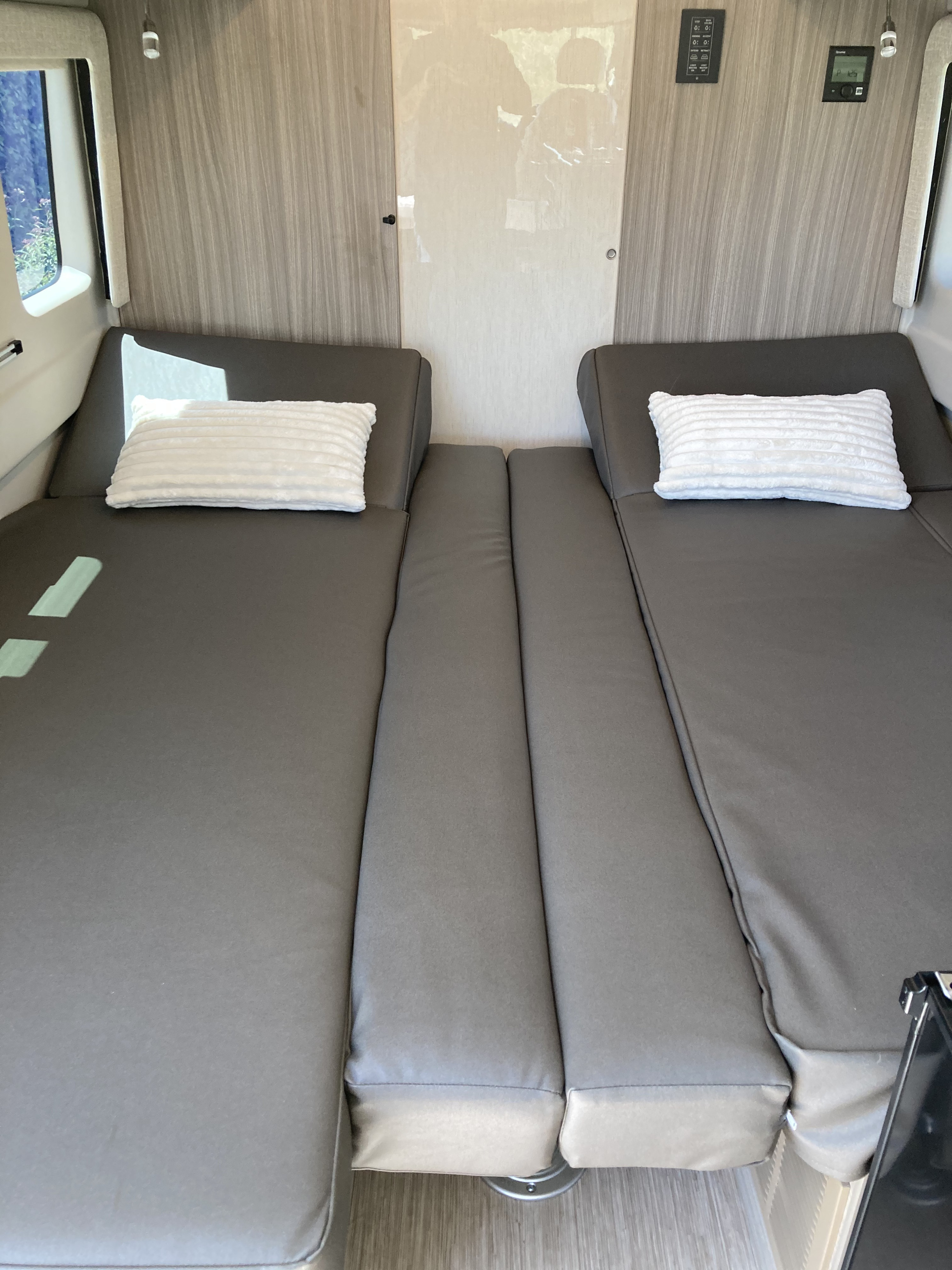 This RV rental offers a compact yet comfortable sleeping area with two long grey beds and white pillows, ready for your journey.. Jayco Swift 2021