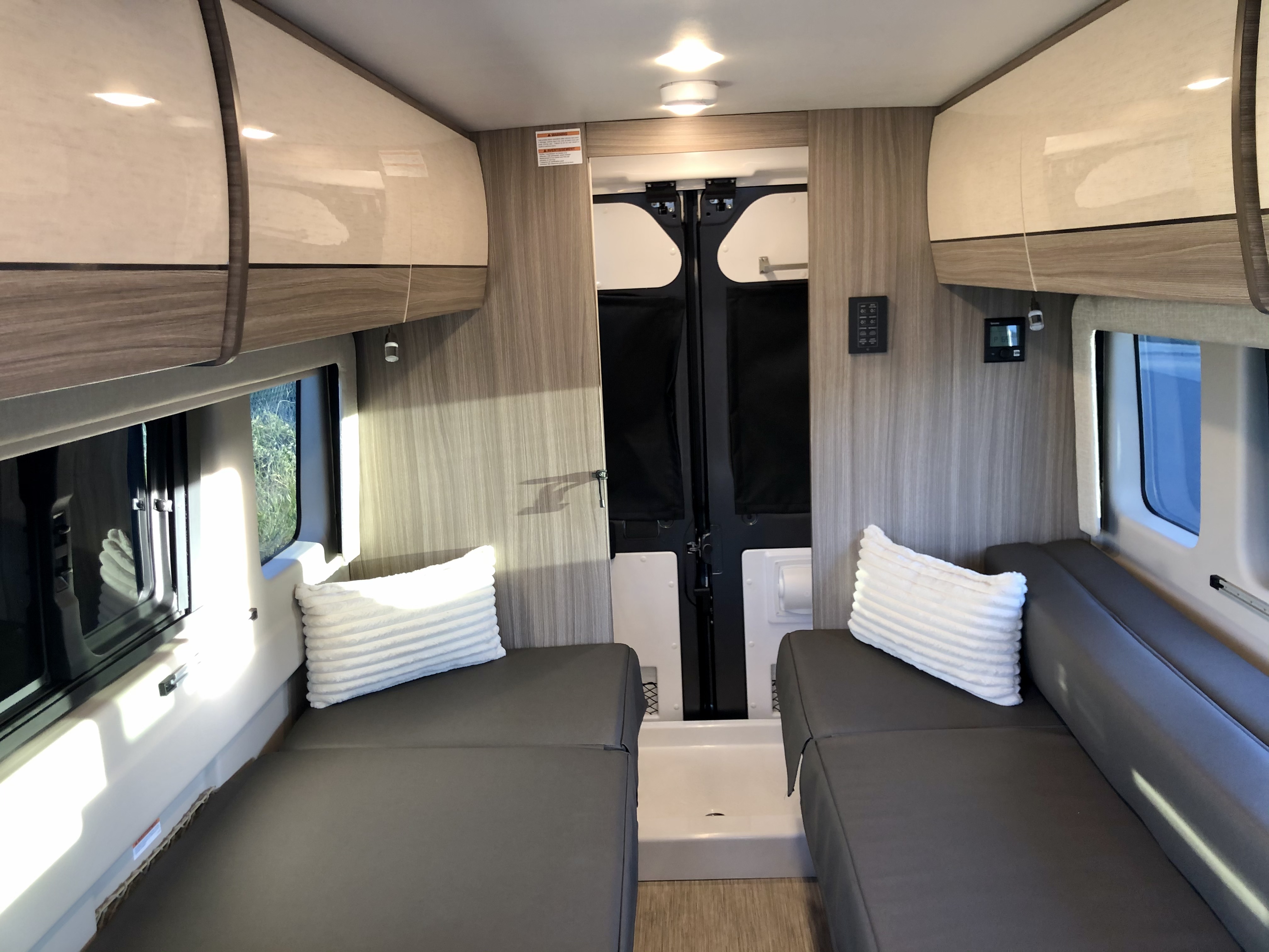 RV rental interior: twin beds flank a central aisle leading to a rear wet bath. Overhead cabinets, windows.. Jayco Swift 2021