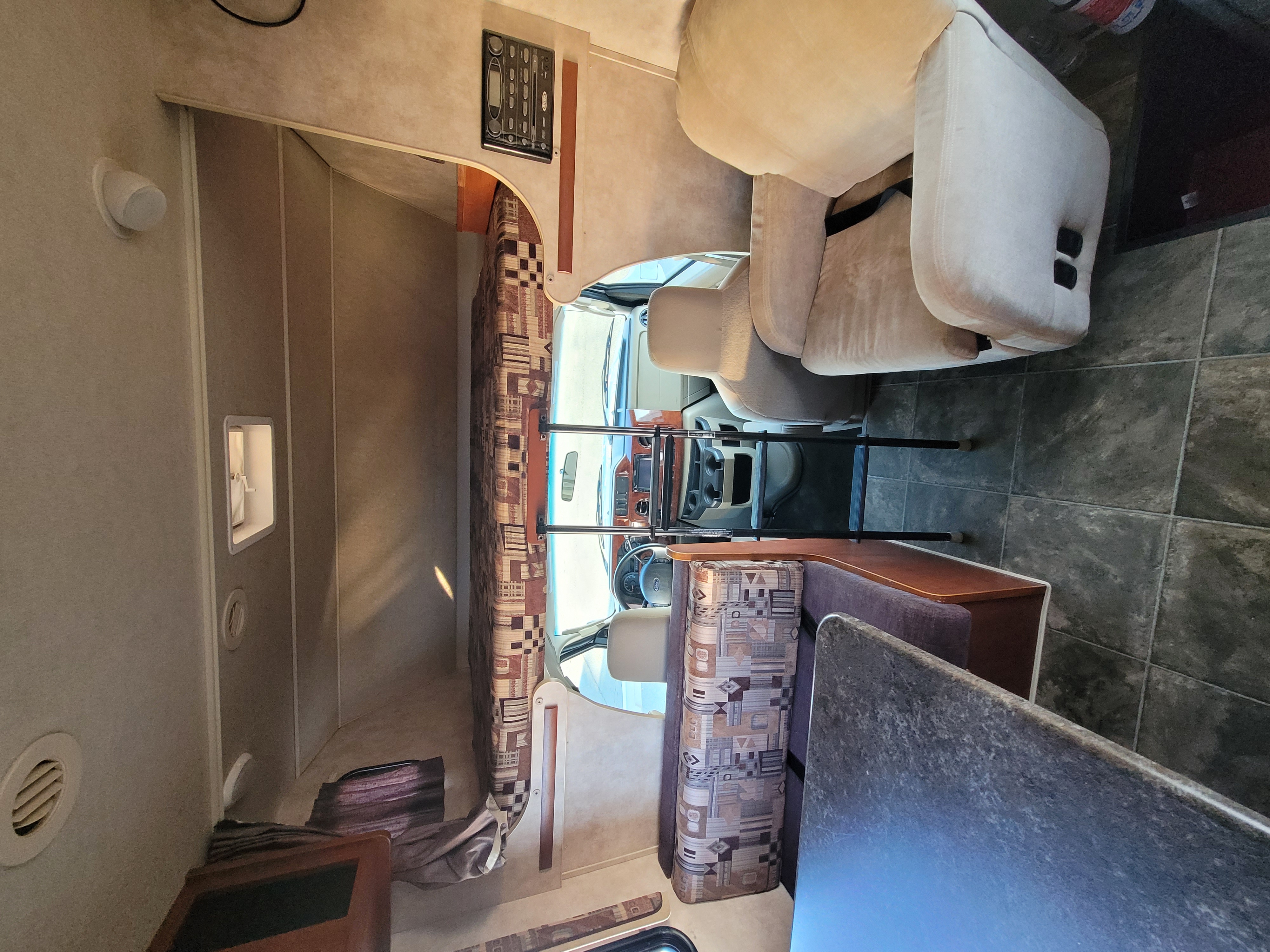 RV rental interior featuring a cab-over bunk, cockpit access, and comfortable living area with dinette. Perfect for road trips!. Winnebago Chalet 2013