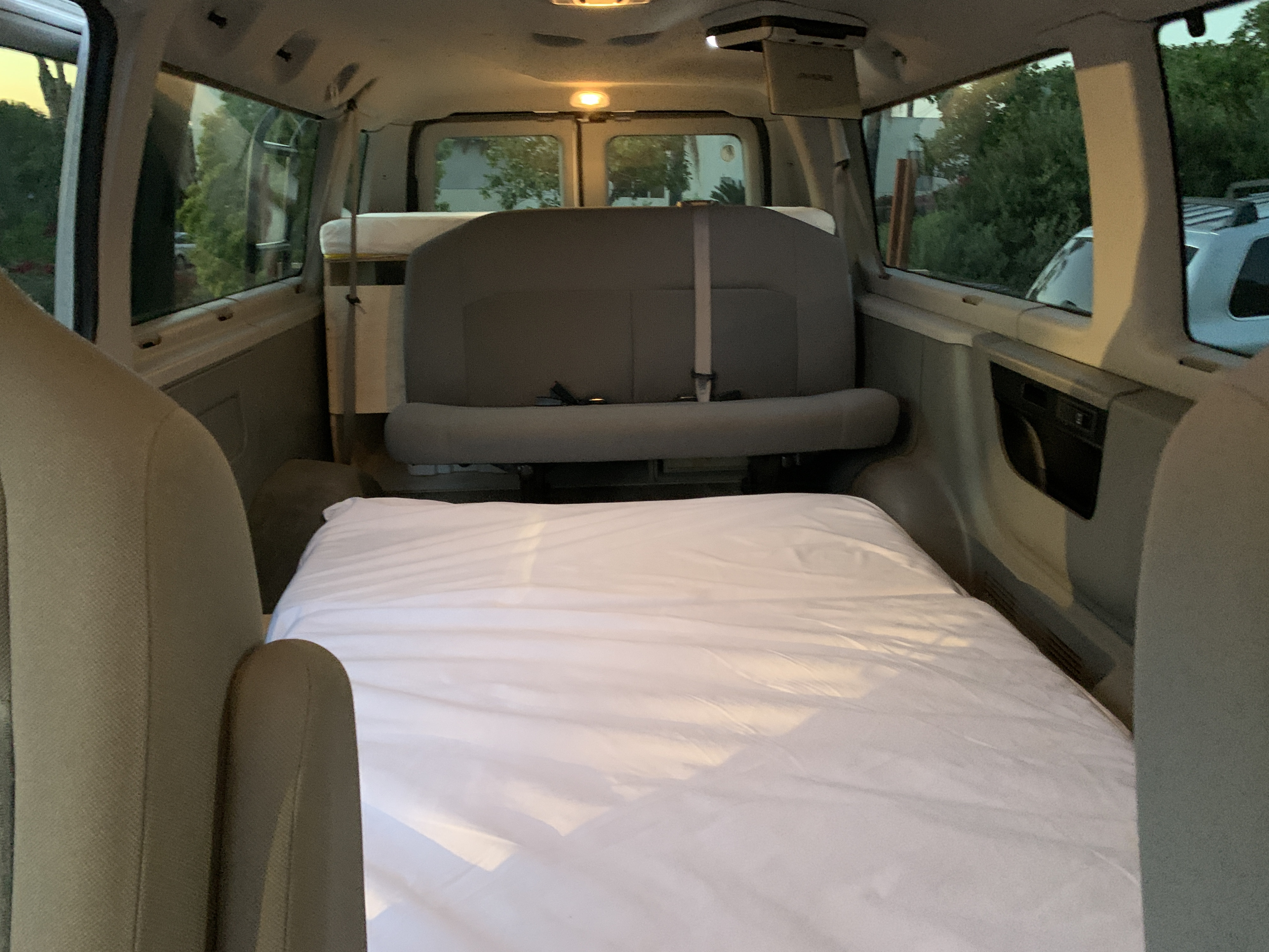 Inside this rv rental van: a well-made bed and passenger seats, ideal for road trips & comfortable travel.. Ford Ford E350 2014