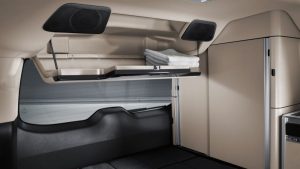 RV rental's compact sleeping area: Shows a bed, overhead storage compartments, and ceiling-mounted speakers.. Mercedes MARCO POLO 2023