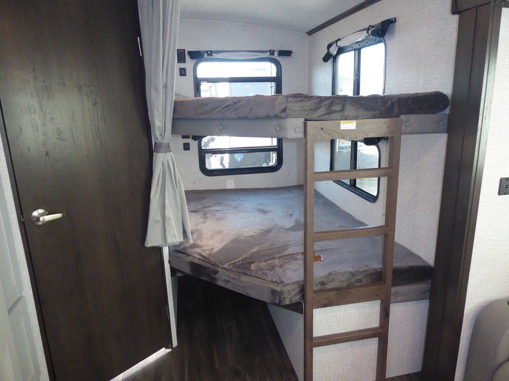 An RV rental interior features two comfortable bunk beds with a ladder and windows. Ideal for family camper trips.. Keystone Bullet 2021
