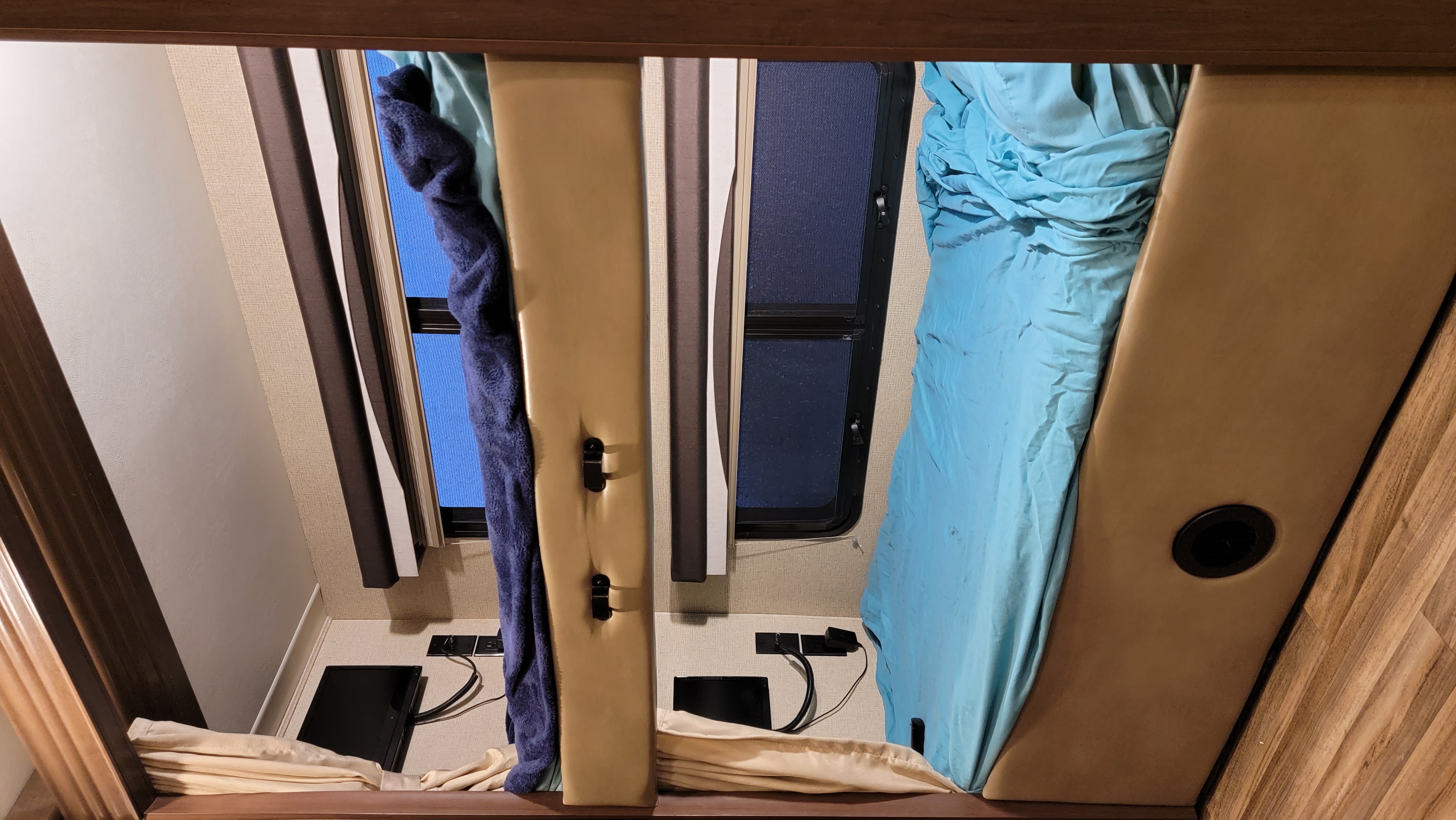 RV rental interior: A compact bunk with side windows, blue bedding, and charging stations.. Thor Motor Coach A.C.E 2017