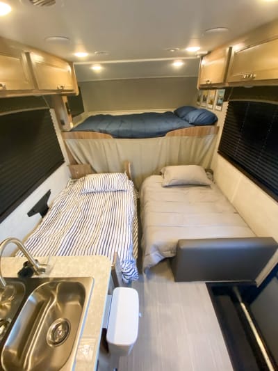 RV rental interior: cozy sleeping area with overhead bunk, two single beds, and a compact sink. Perfect for adventure!. Jayco Redhawk 2021