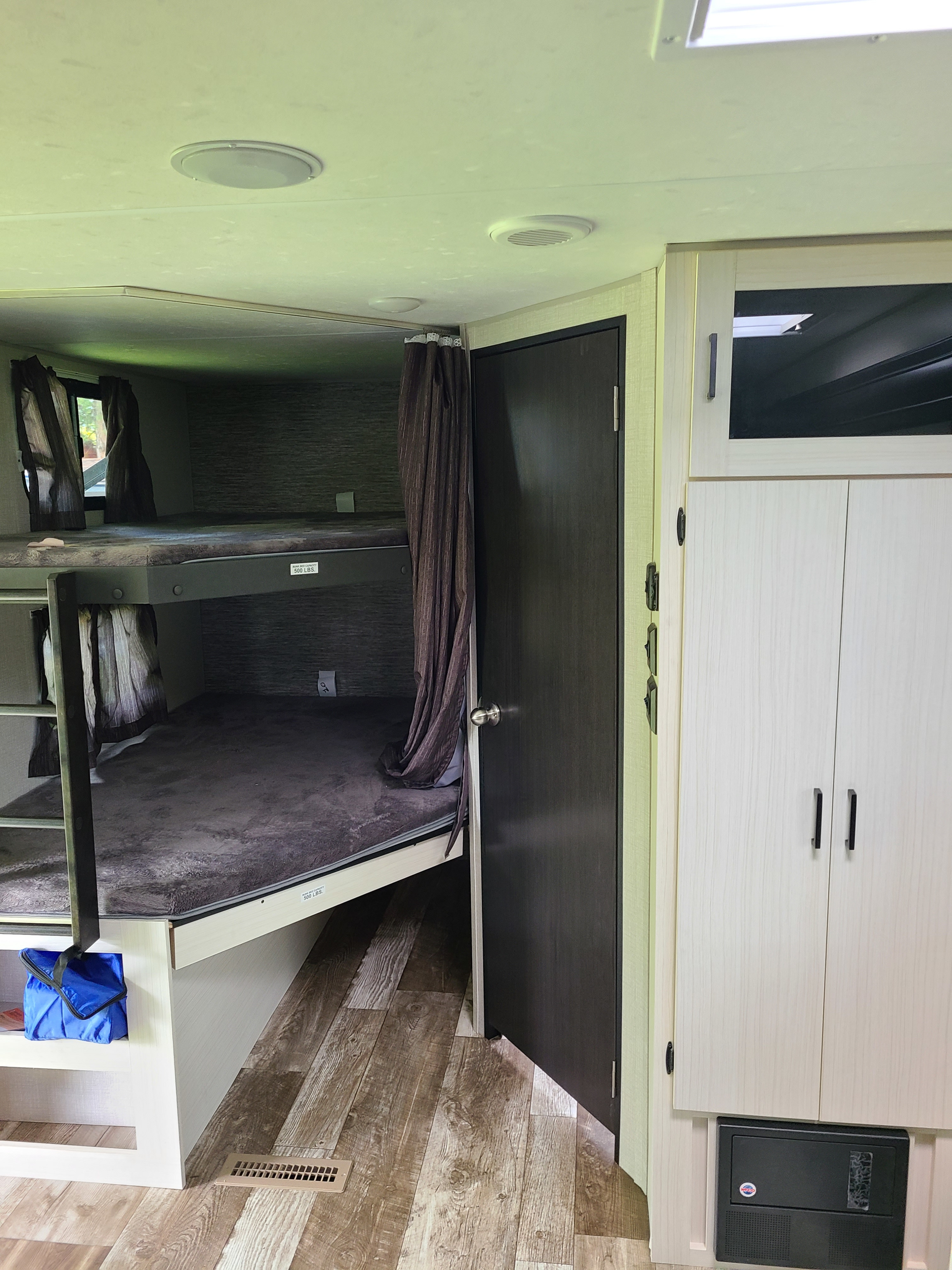 RV rental: bunk beds with privacy curtains, a door, and storage cabinet with a fuse box. Functional interior for travel.. Venture Rv 261 VBH 2021