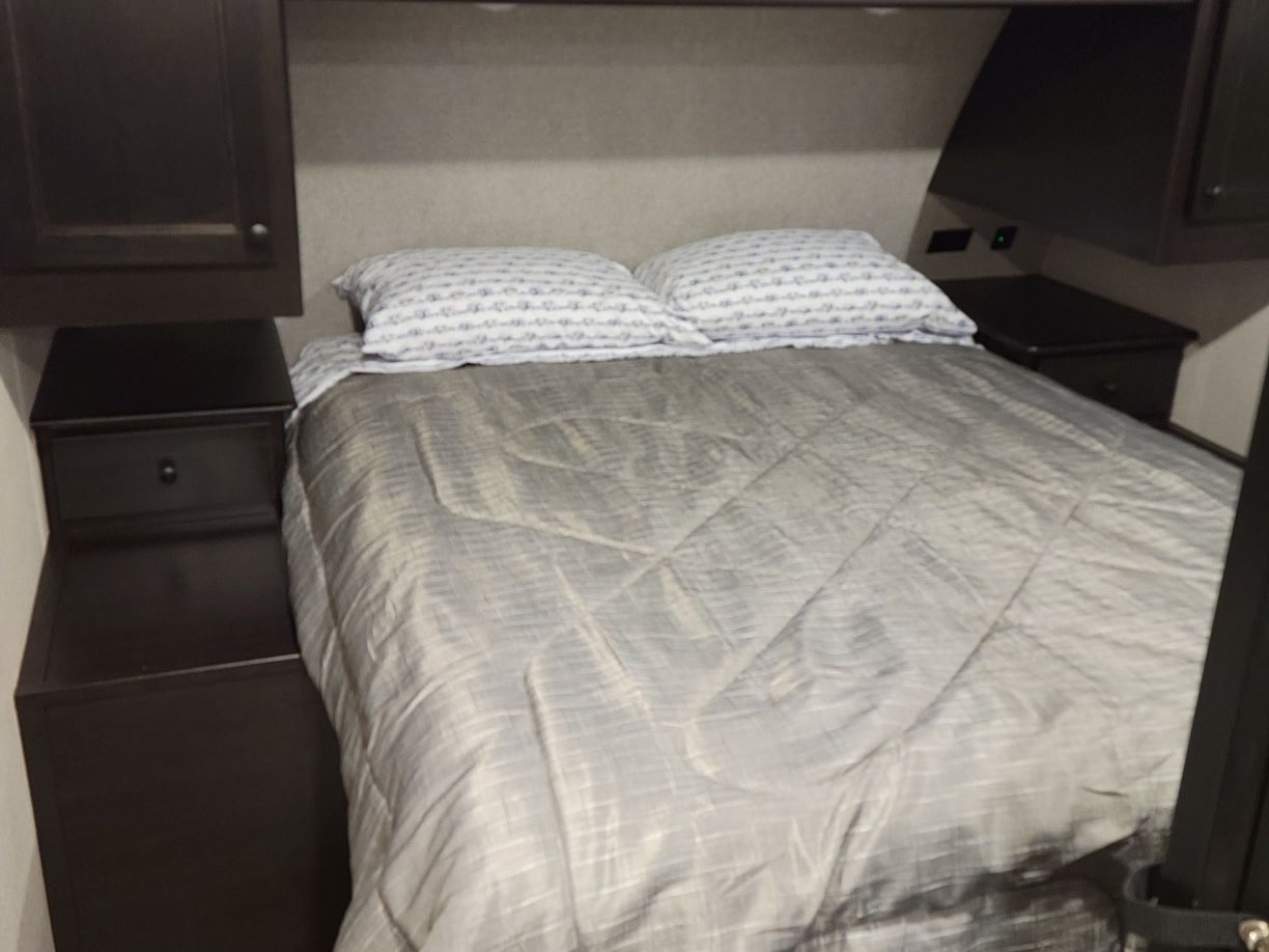 Compact and comfortable RV rental bedroom featuring a bed, nightstands, and overhead storage. Ideal for a cozy stay.. Highland Ridge RV Open Range 2021