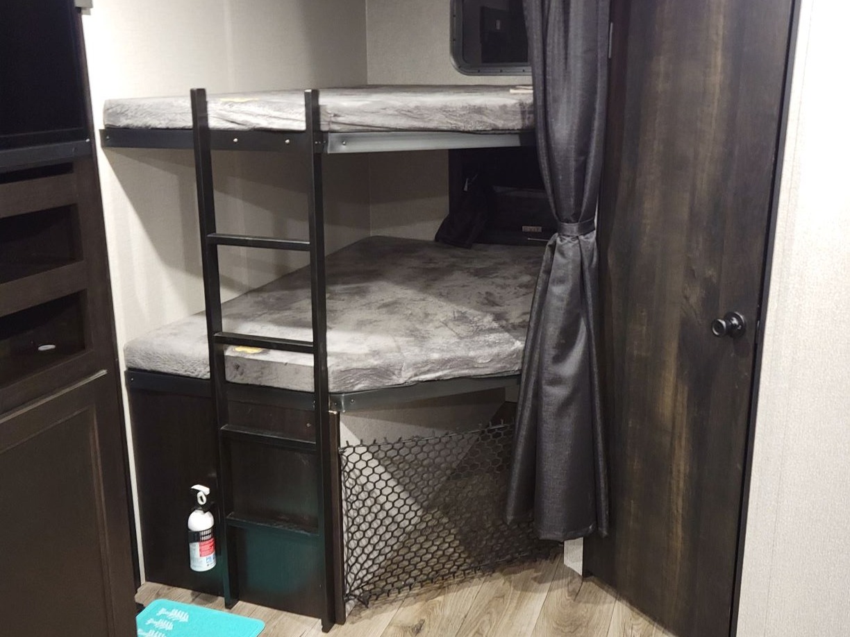 RV rental bunk beds with ladder, privacy curtain, built-in storage, and fire extinguisher for safety.. Highland Ridge RV Open Range 2021