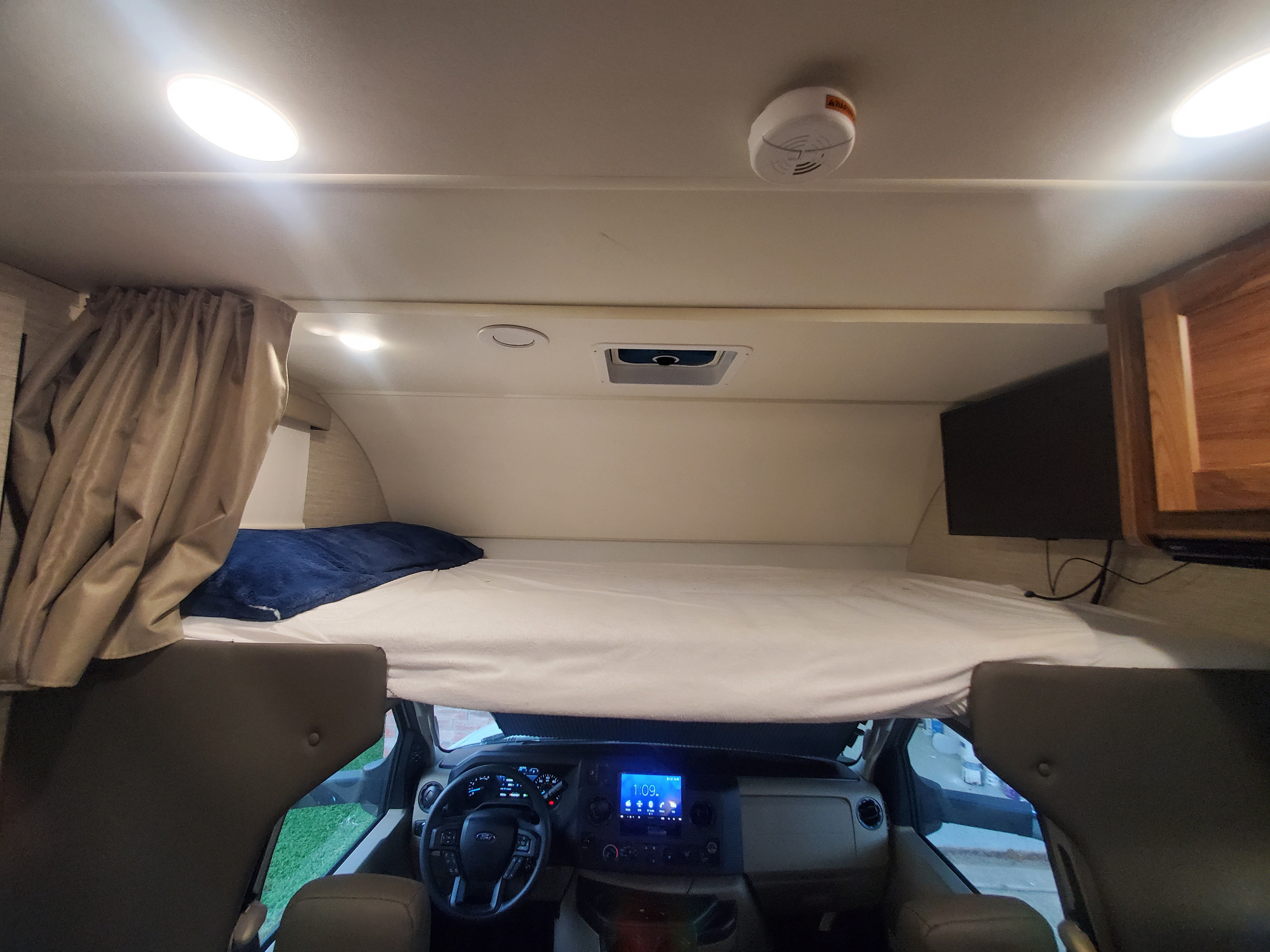 Spacious overhead bunk and driver's cab in this cozy RV rental. Features a comfortable bed, TV, and modern dashboard.. Winnebago Minnie Winnie 2021