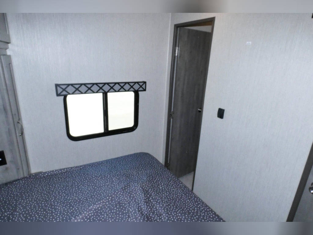 Compact RV rental bedroom featuring a comfy bed, window, and door. Ideal for your next adventure.. Forest River Work And Play 2021
