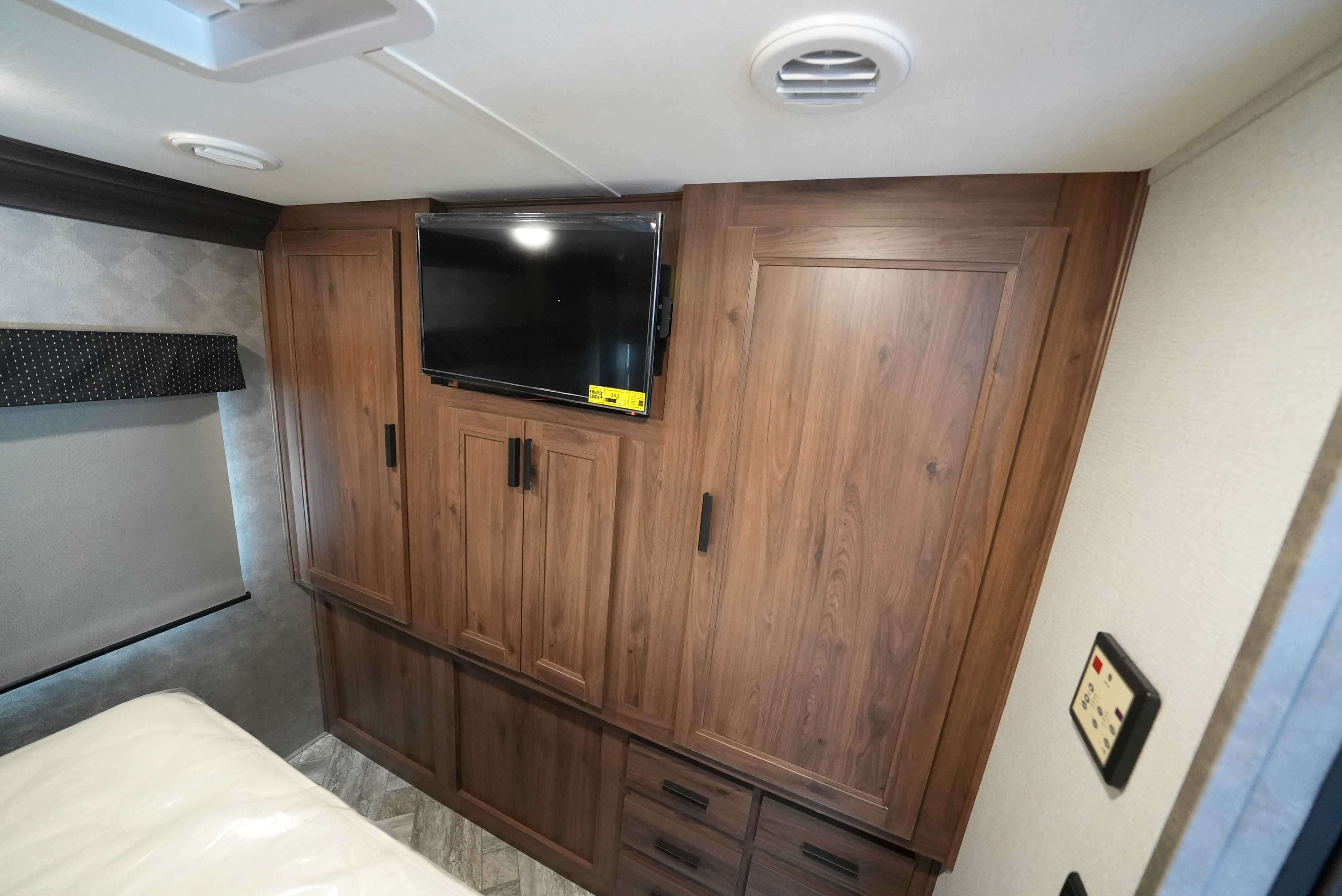 RV rental bedroom with mounted TV, extensive wooden cabinets & drawers, and a mattress, providing practical storage and comfort.. Forester 3011DSF 2021