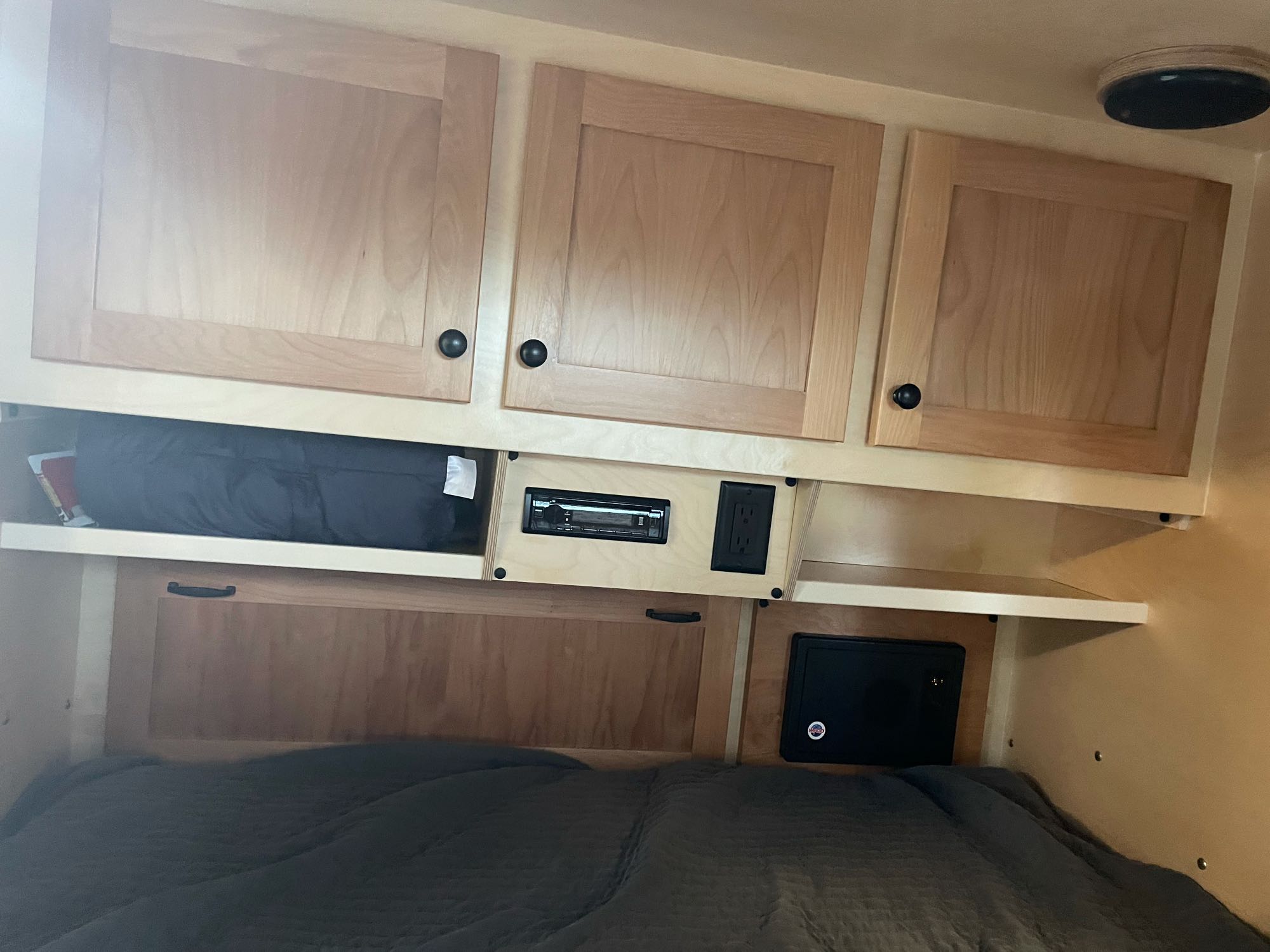 This cozy RV rental interior features wooden cabinets, a stereo, power outlet, and a comfortable bed, maximizing compact living space.. Aero Teardrops Teardrop Camper 2022