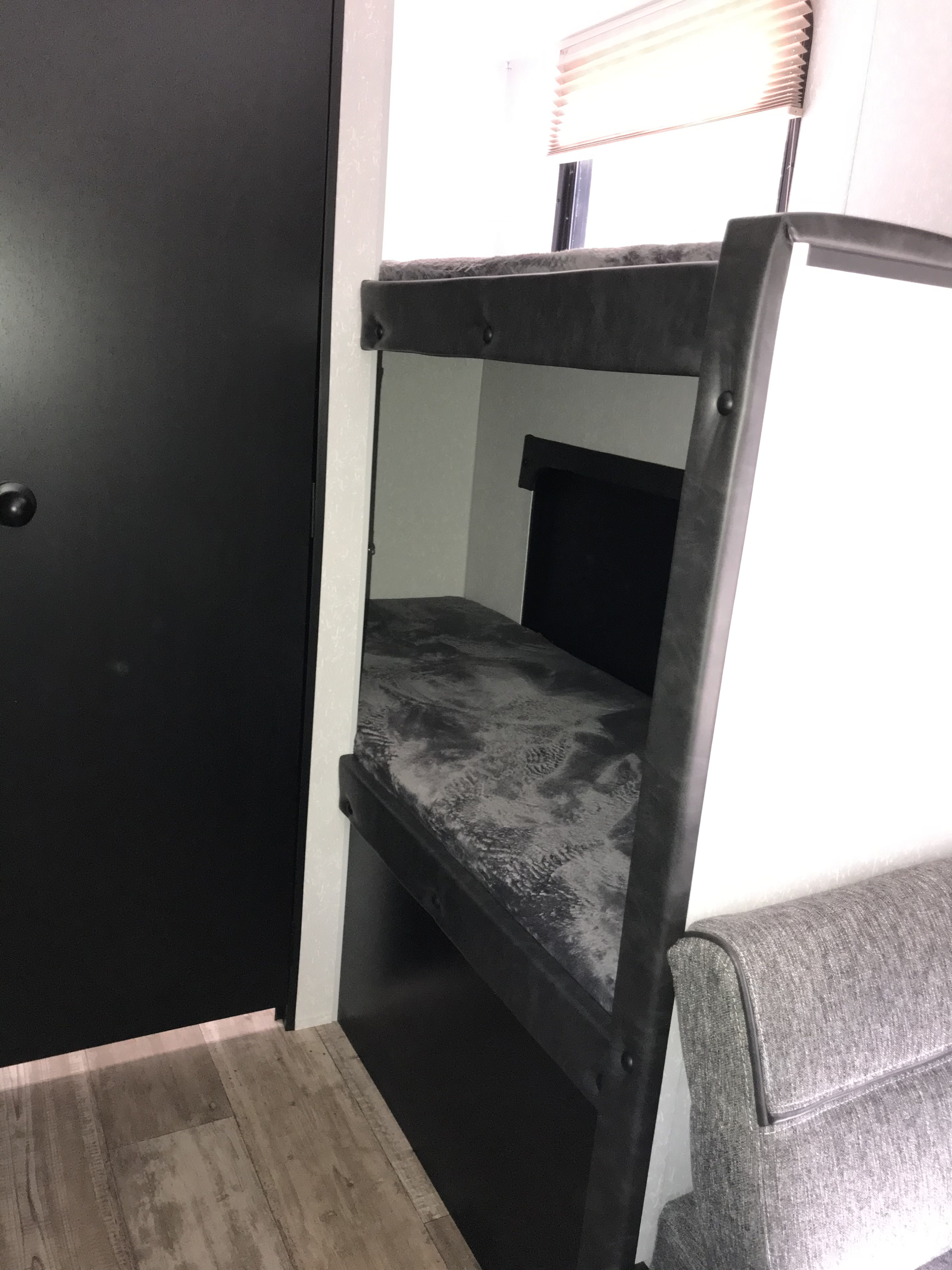 Inside this RV rental: functional bunk beds & a sofa. A compact, modern space ideal for travel adventures.. Forest River Wolf Pup 2021