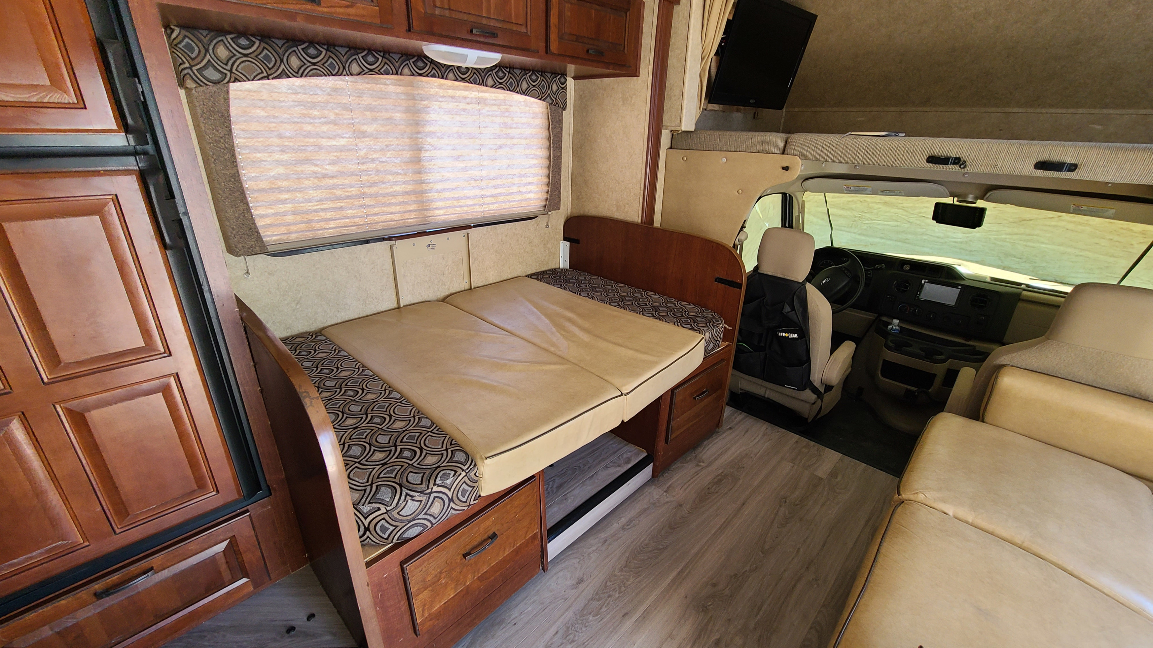 RV rental interior showcasing a cozy dinette, overhead bunk bed, and driver's cab area.. Forest River Sunseeker 2014