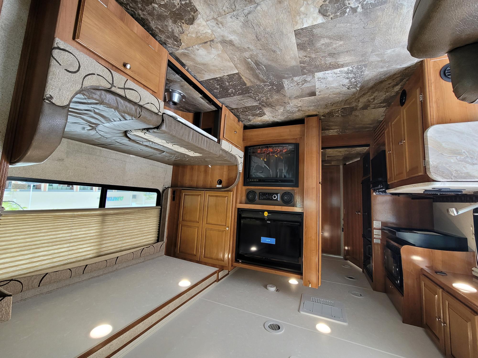 Inside this toy hauler RV rental: a flexible living space with raised bunk, entertainment center, and kitchen.. Coachmen Leprechaun 2020