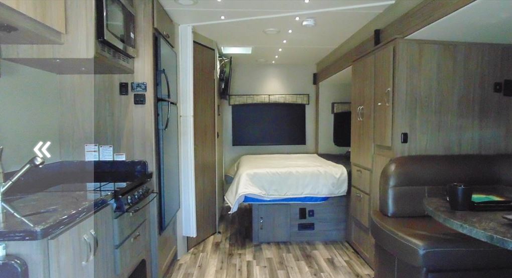 Modern RV rental interior featuring kitchen, bedroom, and dinette areas, offering comfortable travel.. Dynamax Corp Isata 2016