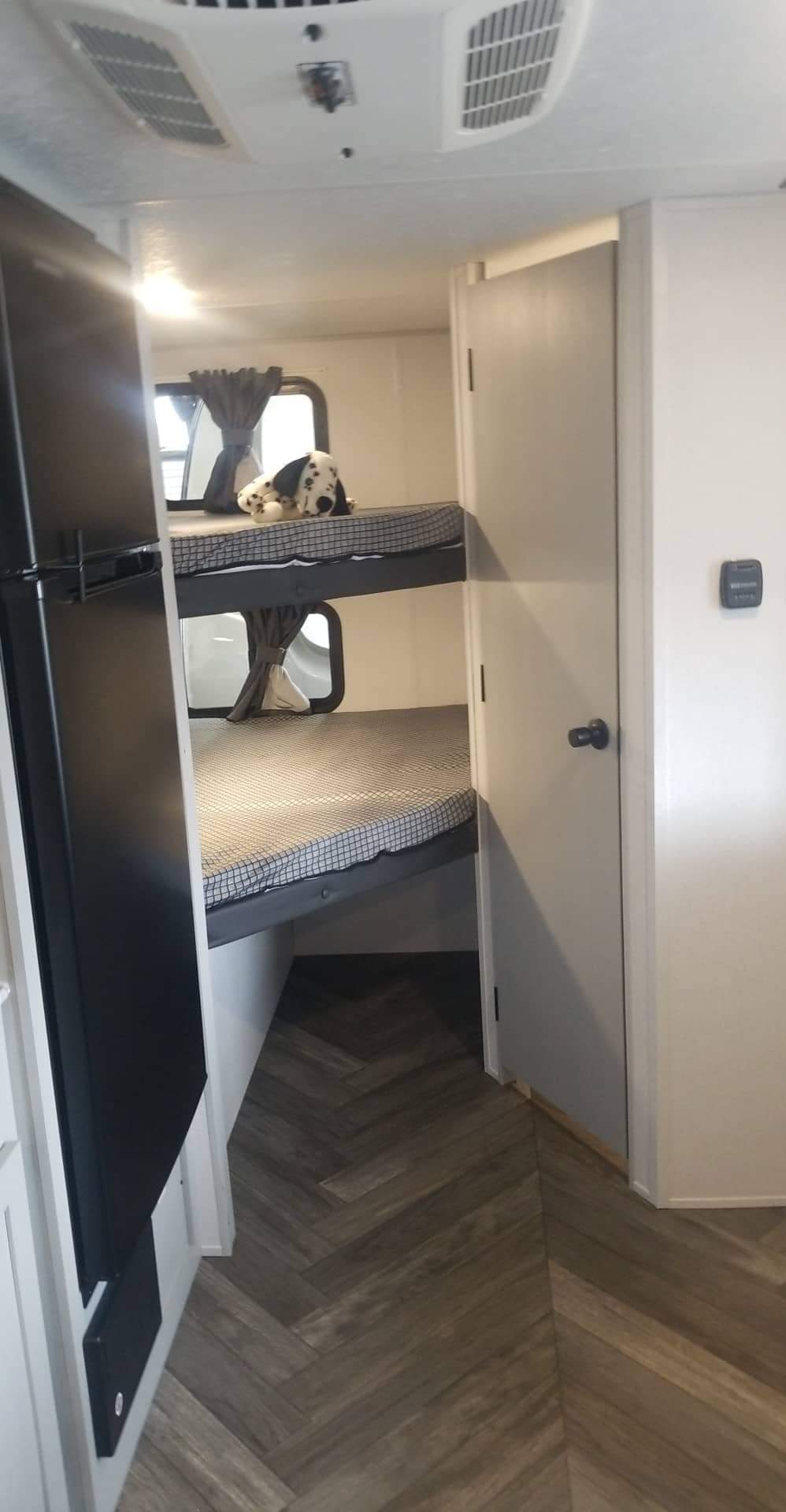 Cozy RV rental interior with bunk beds, a Dalmatian plushie, and a fridge, perfect for family travel.. Forest River Wildwood 2021