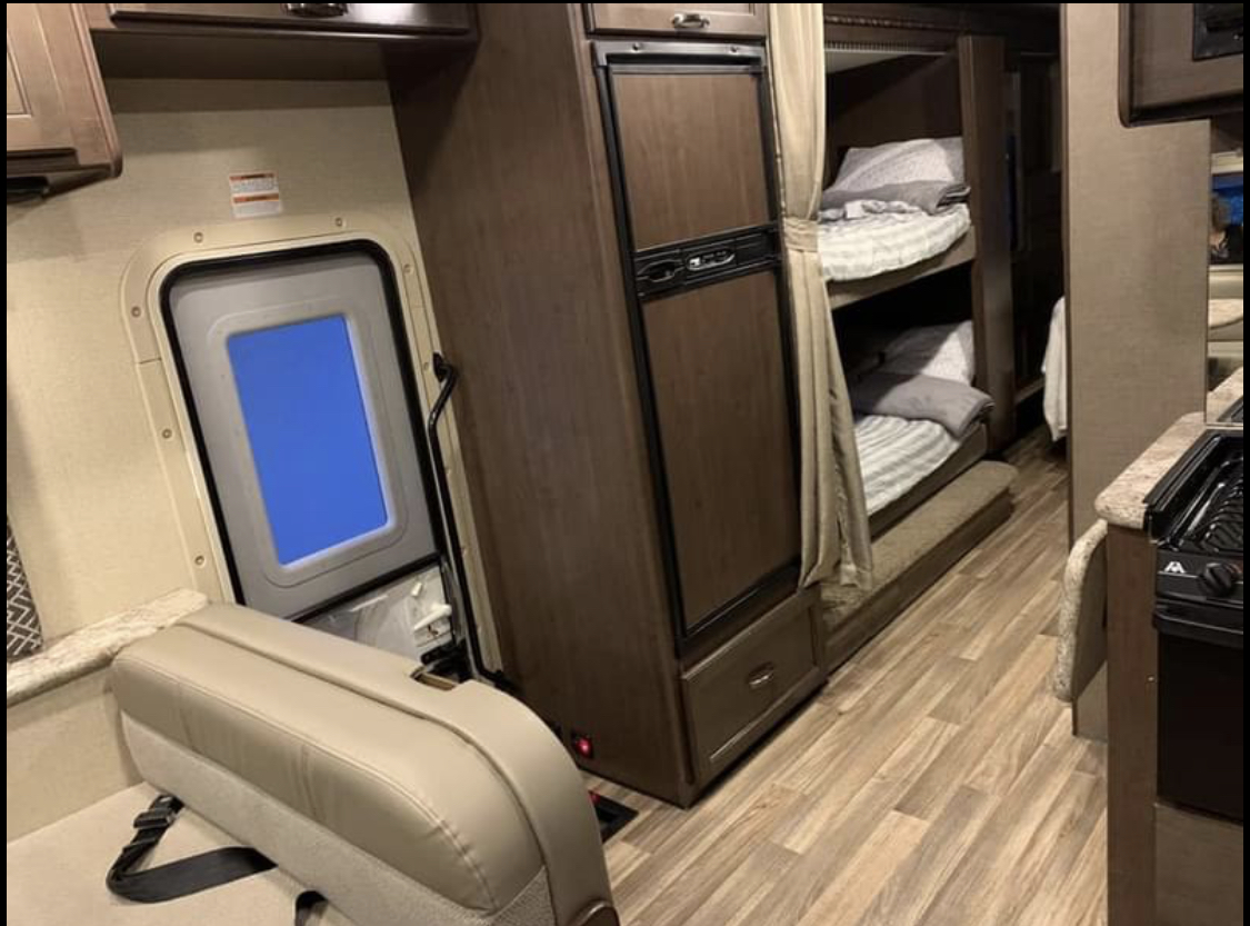 Inside an RV rental: a cozy space with bunk beds, a compact kitchen, and seating near the exit door. Perfect for family adventures.. Thor Motor Coach Four Winds 2019