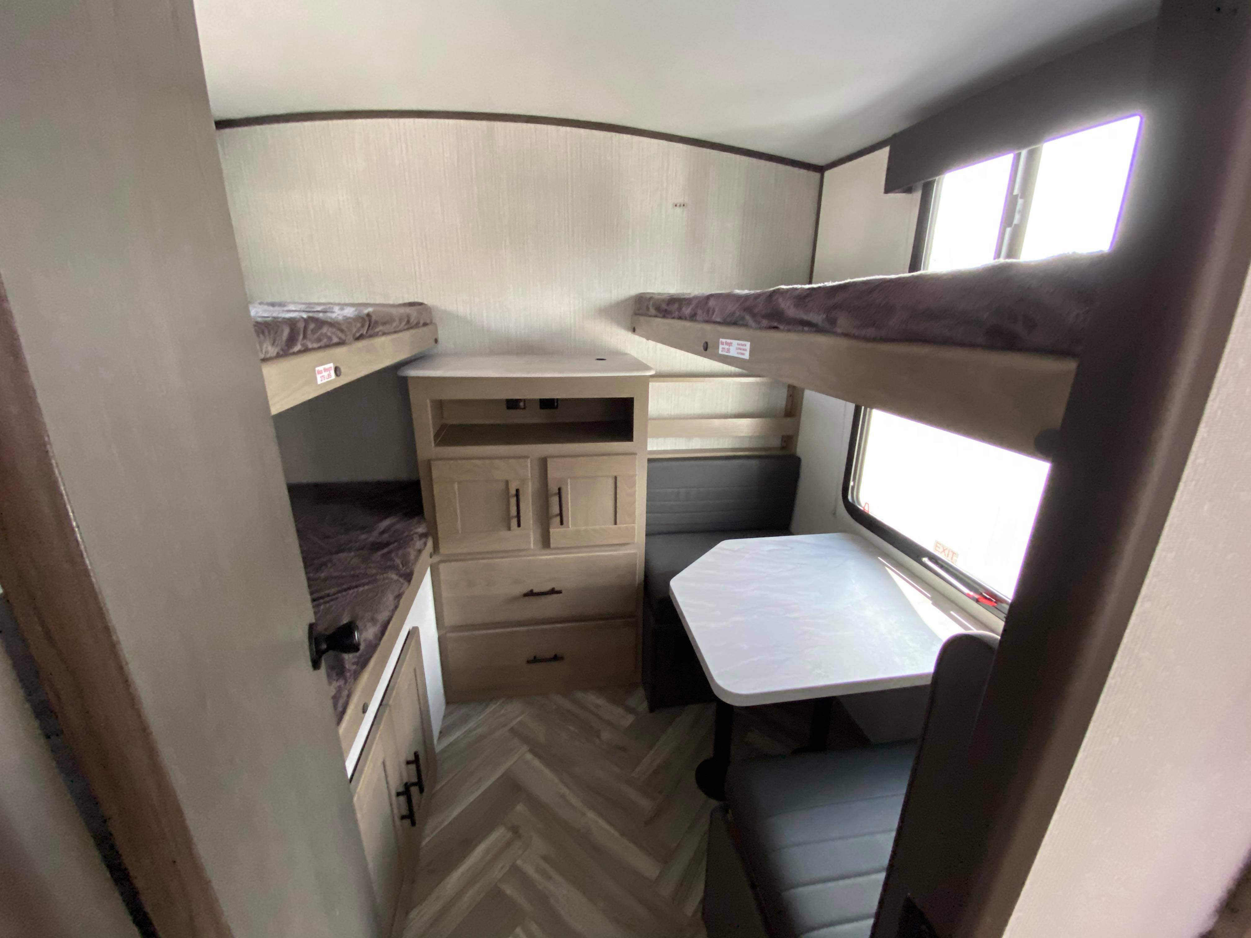 Cozy RV rental interior featuring bunk beds, a dinette, and central storage, ideal for family adventures.. Cruiser Rv Corp Shadow Cruiser 2021