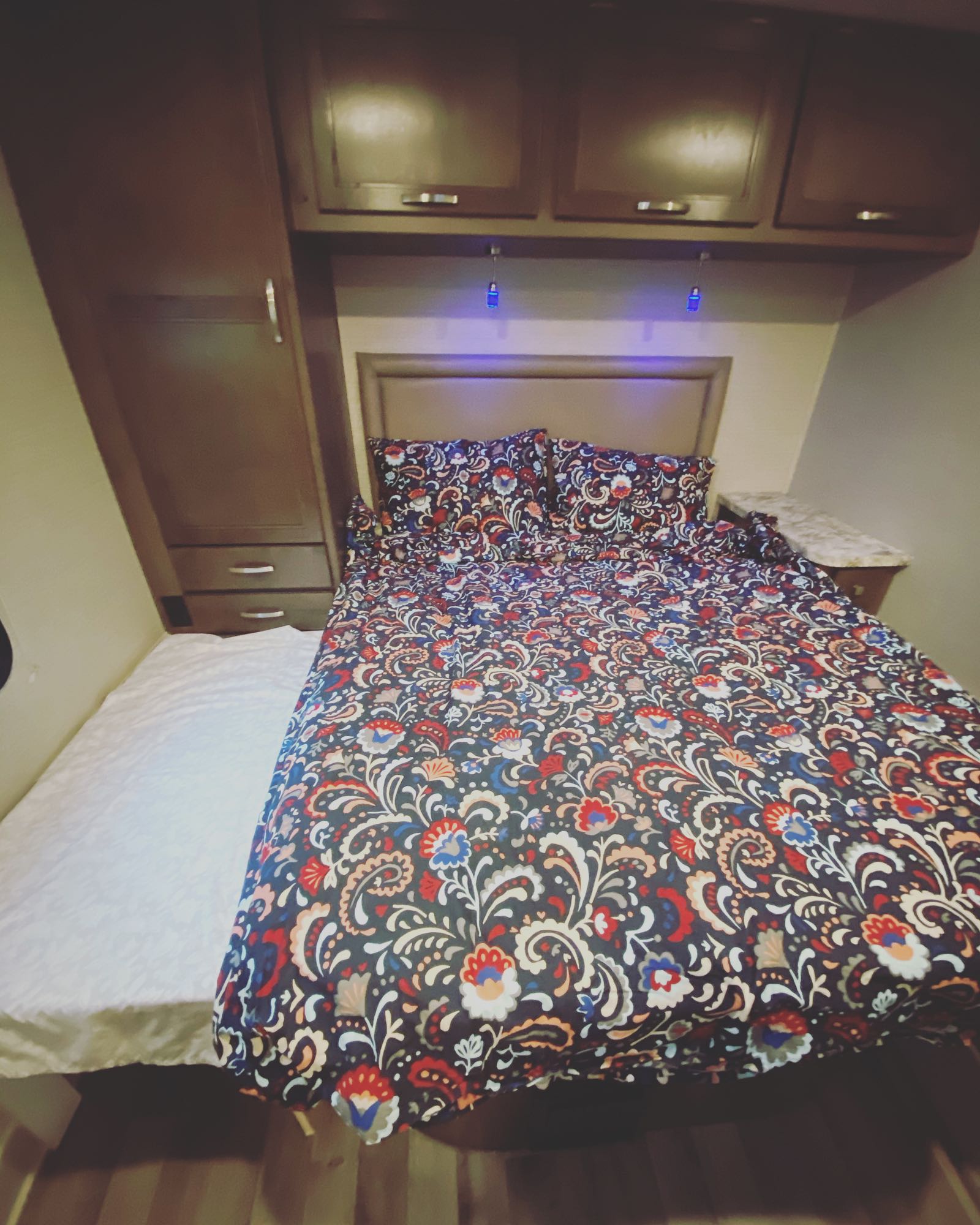 Inviting RV rental bedroom with patterned bed, overhead storage, and second sleeping area.. Jayco Redhawk 2020