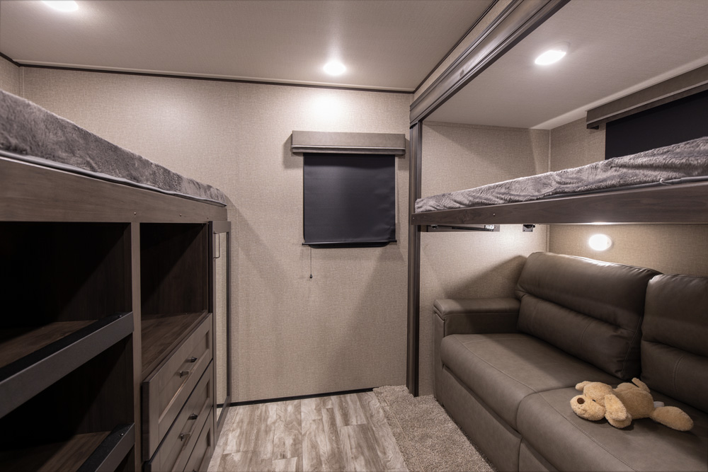 RV rental bunkhouse interior: Cozy bedroom with dual bunk beds, sofa, and built-in storage.. Grand Design Reflection 2020