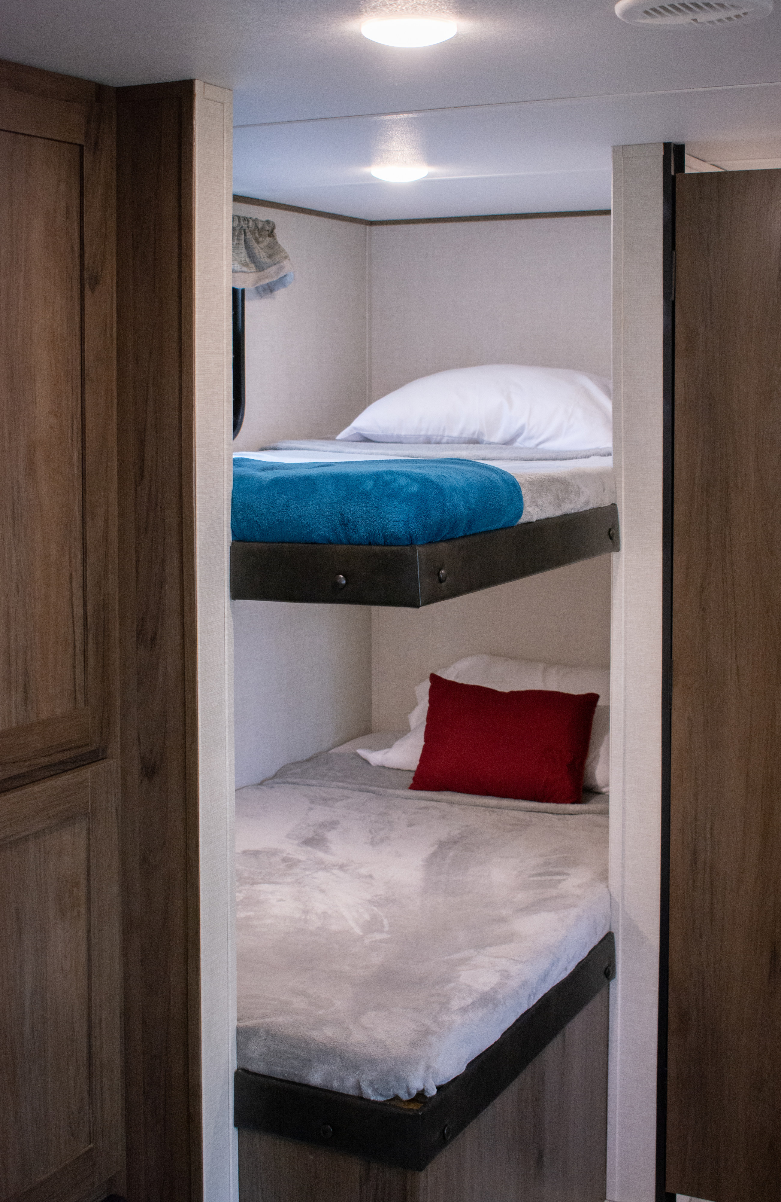 Cozy bunk beds in this RV rental offer comfortable sleeping with blue and red accents. Perfect for road trips!. Prime Time Avenger 2021