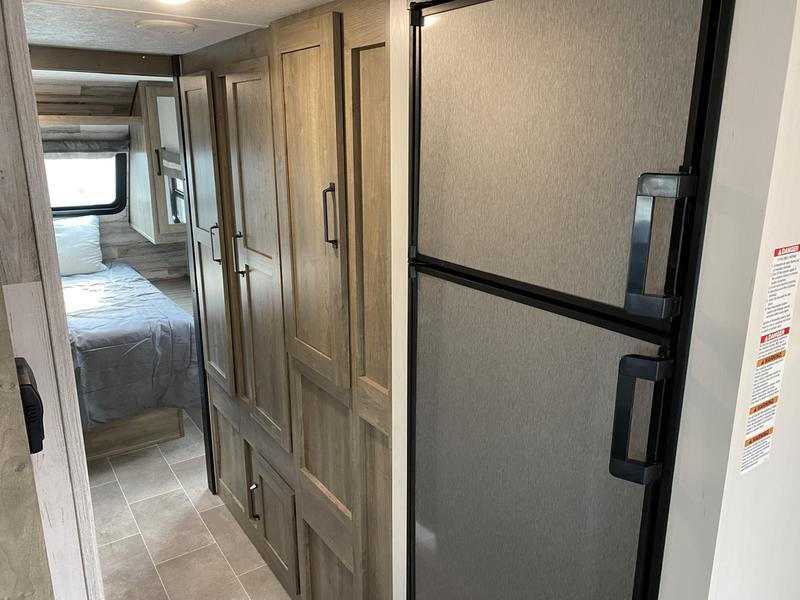 Inside an RV rental: View of the refrigerator, storage cabinets, and a hall leading to the bedroom area.. Forest River Palomino Puma XLE Lite 2021