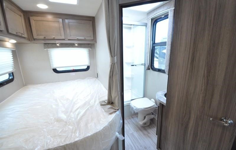 Spacious RV rental features a comfortable bed with overhead storage, connected to a compact bathroom with shower & toilet.. Entegra Coach Entegra 2020