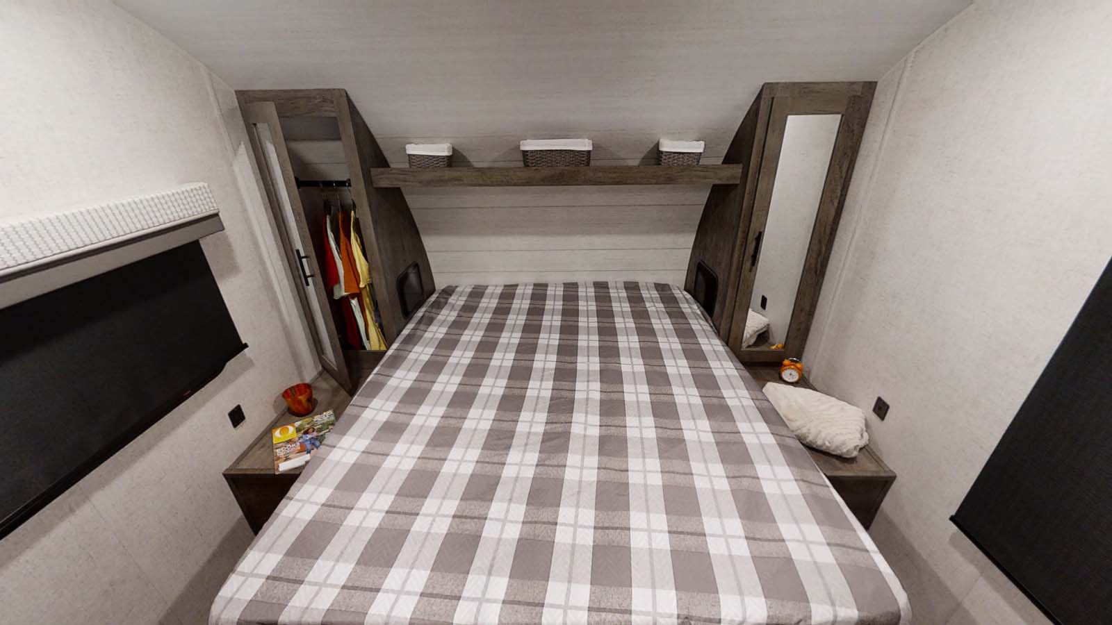 Cozy RV rental bedroom featuring plaid bedding, clever built-in storage, and compact side tables.. Forest River Wildwood X-Lite 2021