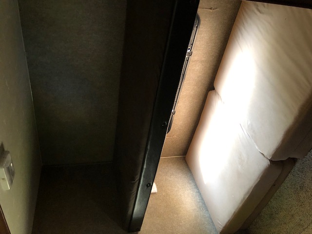 Compact RV rental interior featuring a dark bunk bed and two light-colored cushions, likely a seating or sleeping area.. Coachmen 310 BHDS 2015