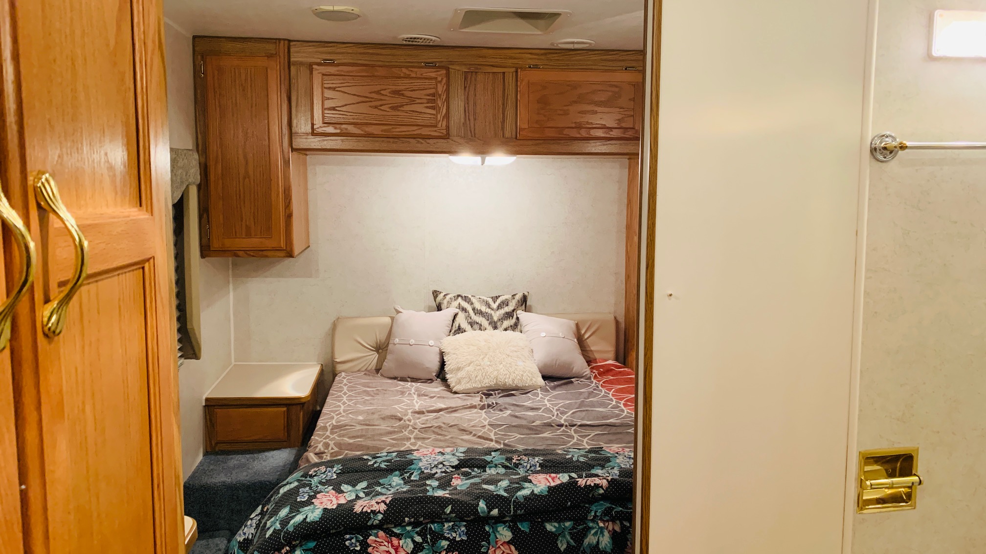 Cozy RV rental bedroom with a comfortable bed, overhead cabinets, and wooden accents.. Gulf Stream Independence 2003