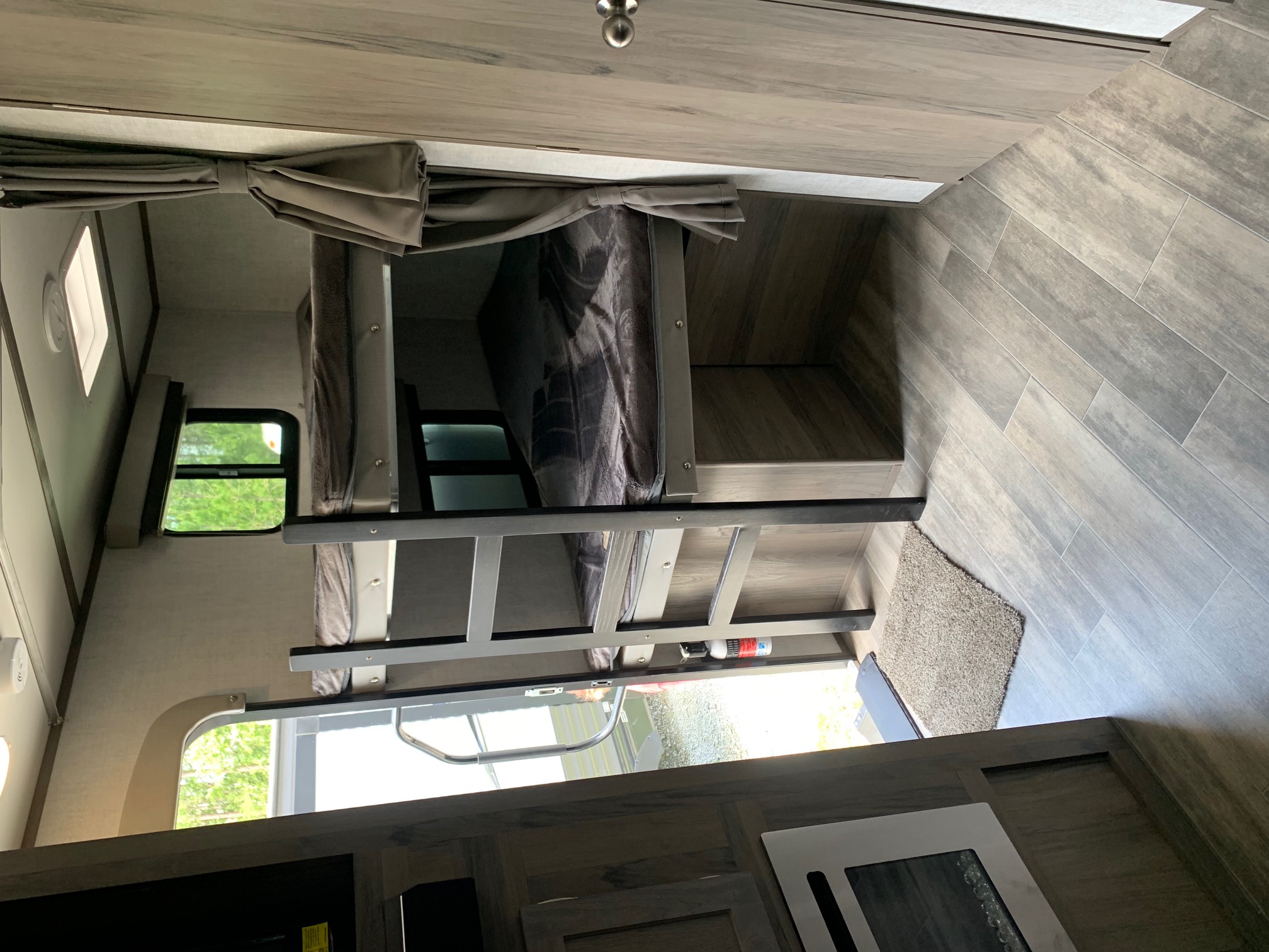 RV rental interior features modern bunk beds with ladder, wood-look flooring, and ample windows. Perfect for family adventures.. Gulf Stream Envision 2021