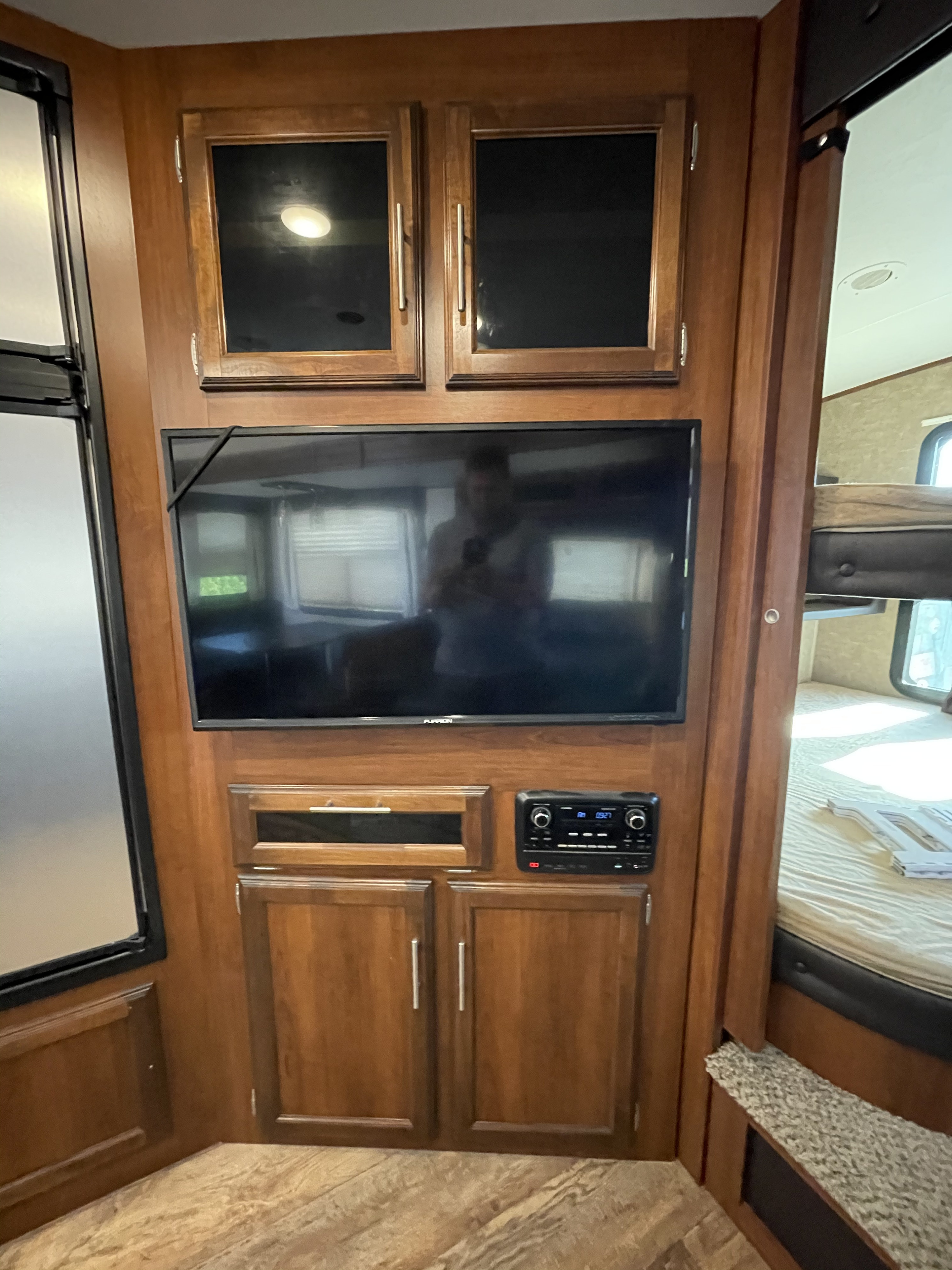 An RV rental interior featuring a mounted TV, stereo, wood cabinets, and a bunk bed, creating a functional space.. Jayco Eagle HT 2017
