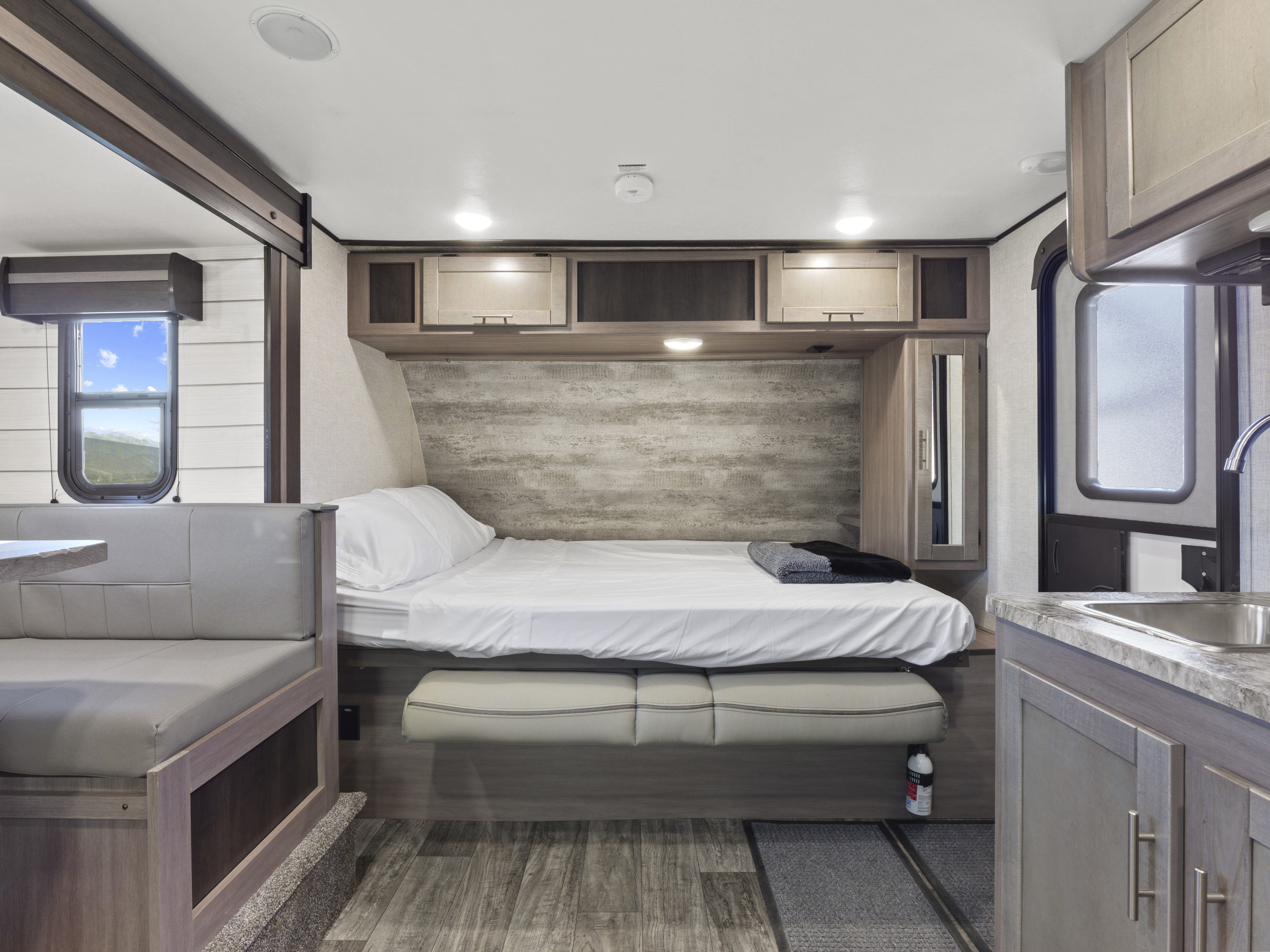 Spacious RV rental interior features a cozy bed, dining booth, kitchen, and scenic window views.. Crossroads Sunset Trail Super Lite 2021