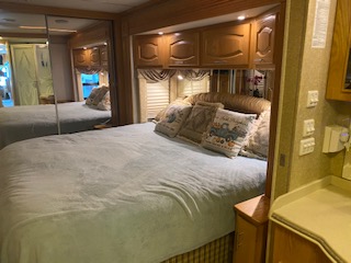 Cozy RV rental bedroom with a comfy bed, mirrored closet, and built-in storage. Ideal for travel comfort.. Newmar Mountain Aire 2005