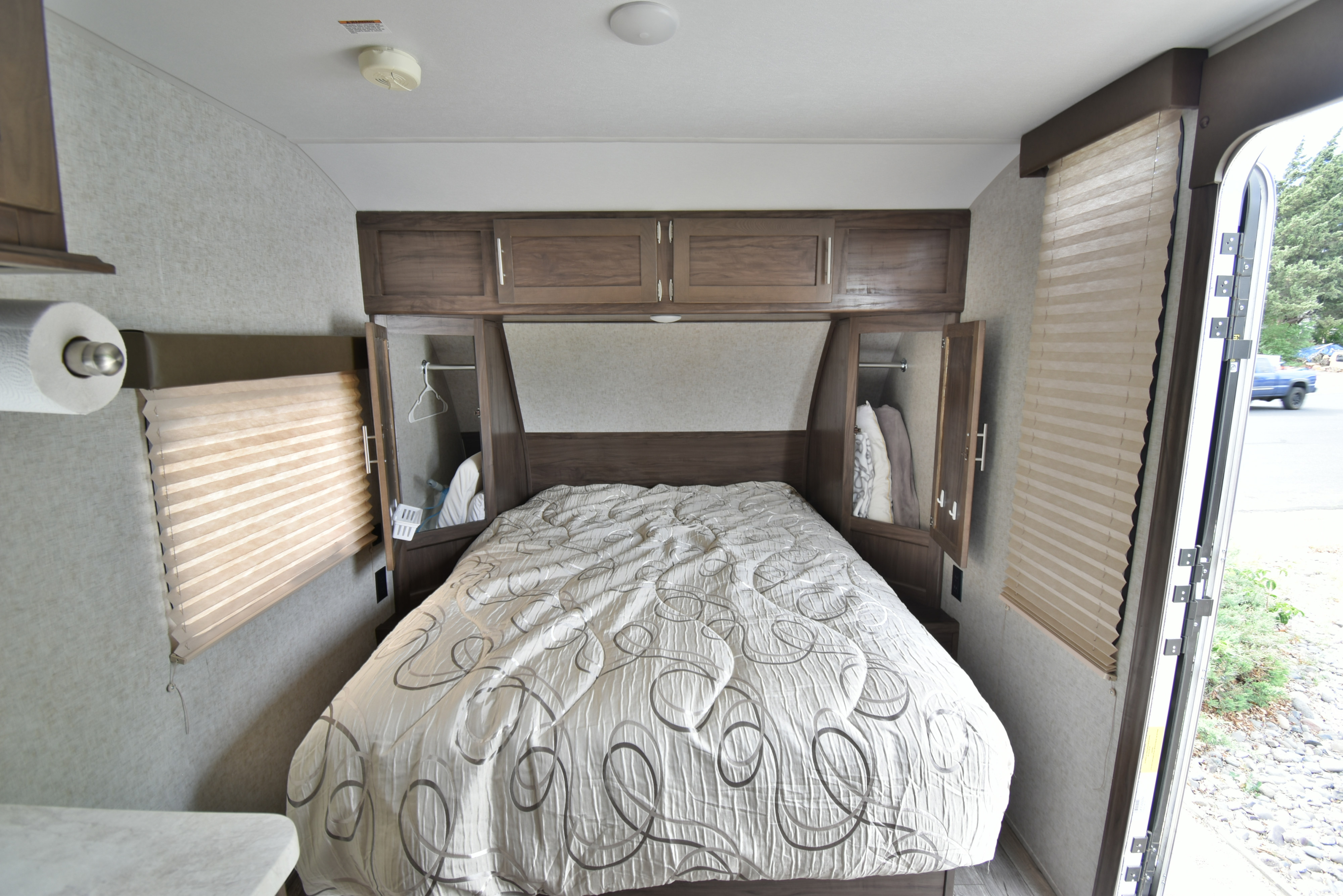 Cozy RV rental bedroom with a large bed, overhead storage, and natural light from the window.. Forest River Cherokee Wolf Pup 2019