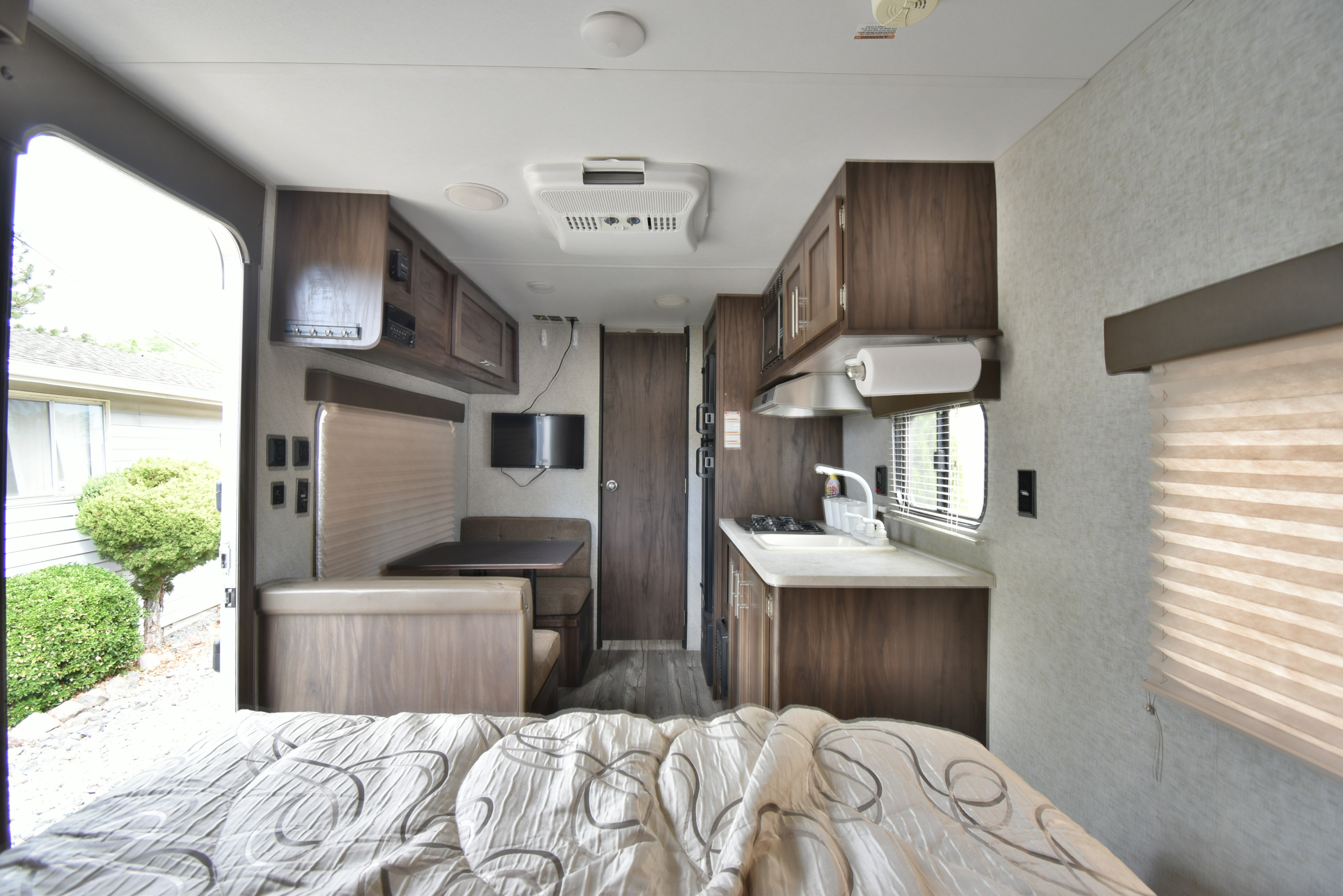 Cozy RV rental interior showing a bed, dinette, and full kitchen. This travel trailer offers comfort for your adventures.. Forest River Cherokee Wolf Pup 2019