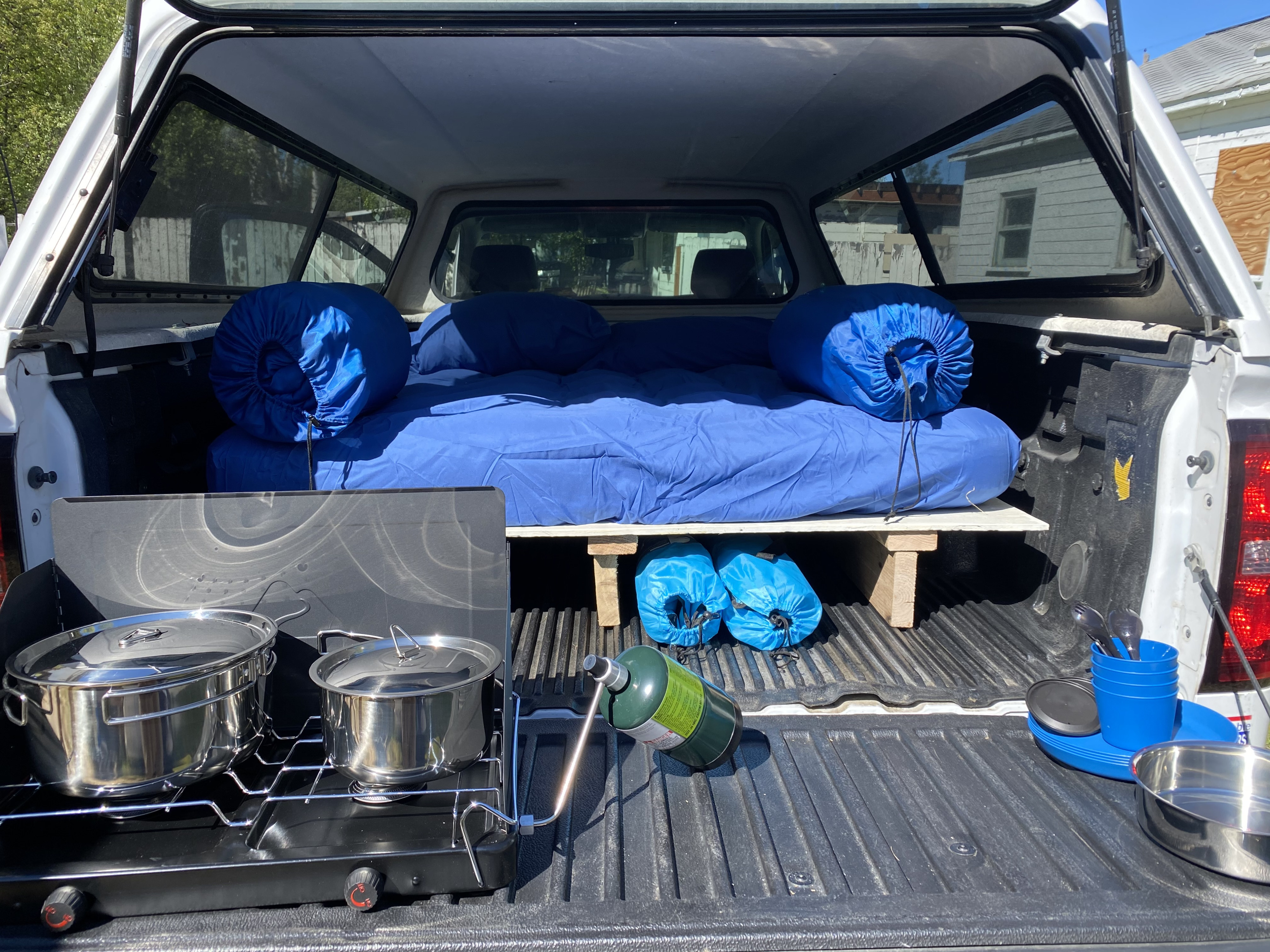 This truck bed camper setup offers a DIY rv rental experience with a cozy sleeping platform and portable kitchen gear.. Chevrolet Silverado 2015
