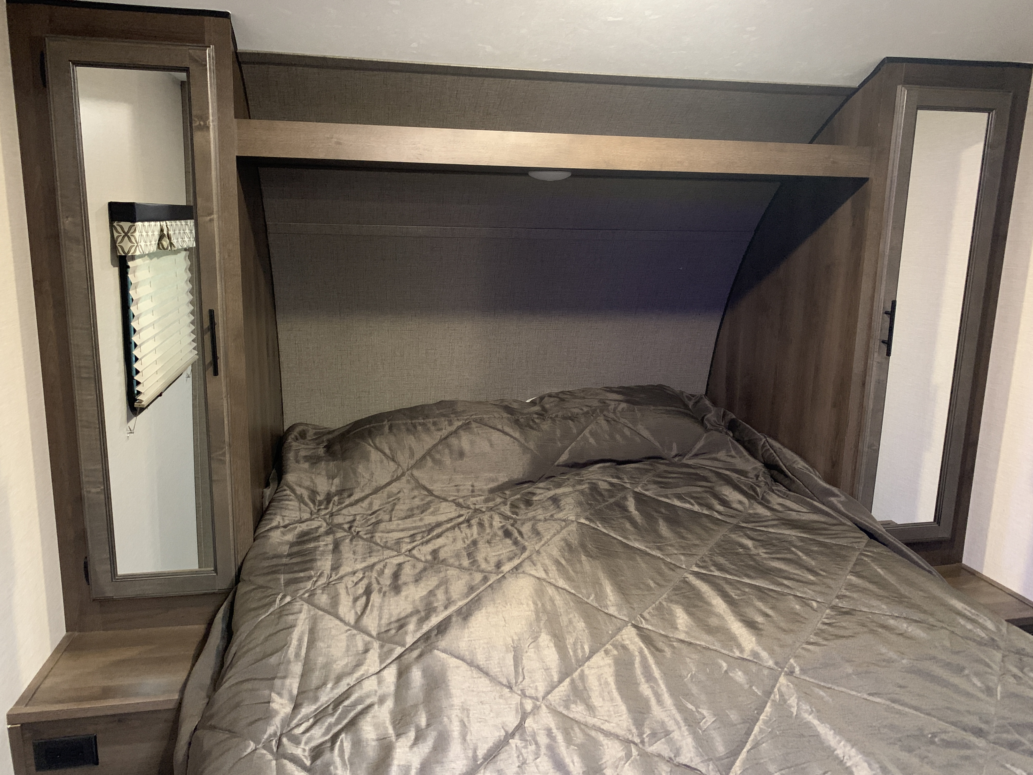Experience comfort in this RV rental bedroom. Features include a cozy bed, overhead storage, and mirrored bedside cabinets.. K-Z Manufacturing Connect 2018