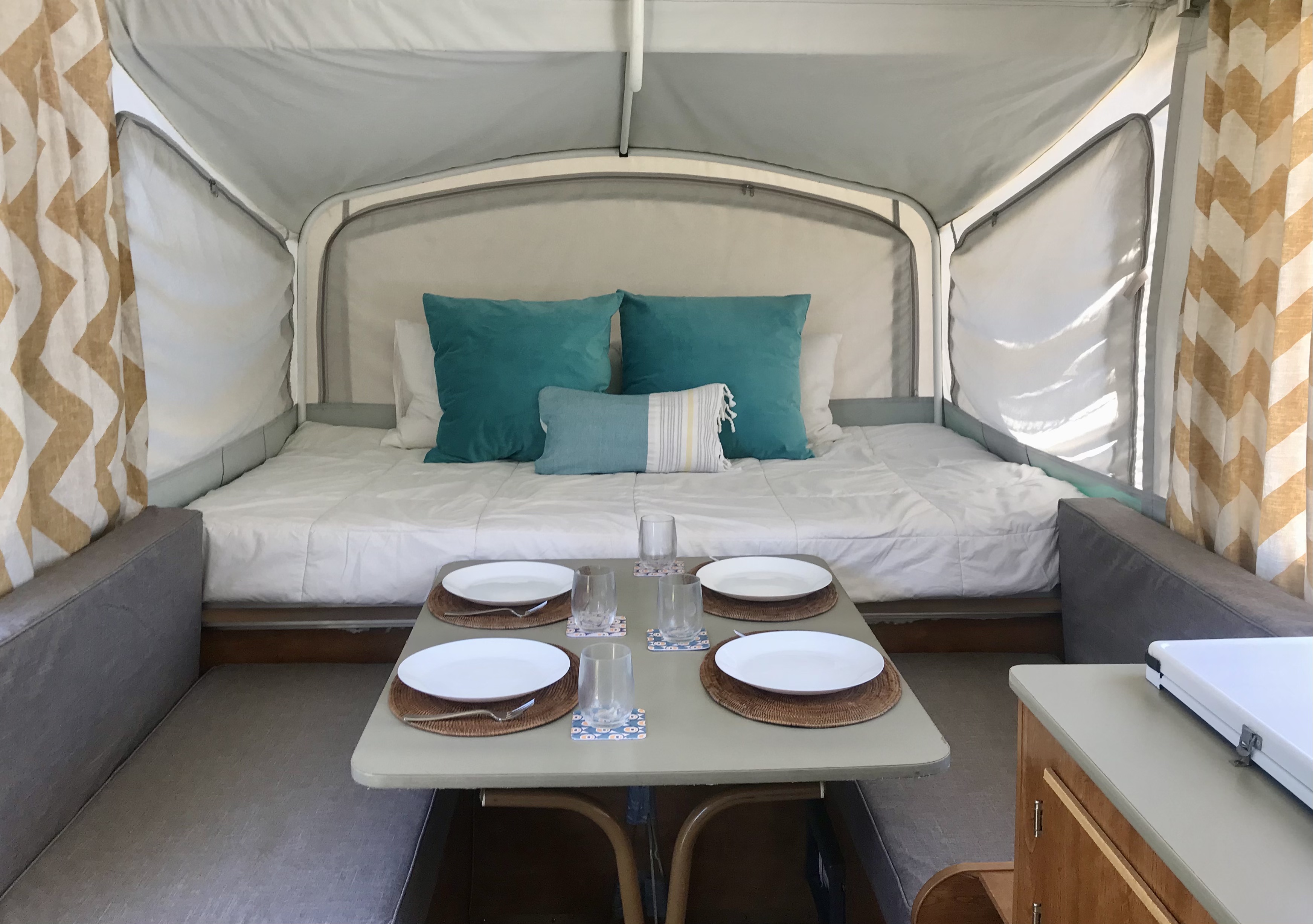 RV rental's inviting interior: bed with blue pillows, dining area with full place settings for a comfortable stay.. Fleetwood Sea Pine 2006