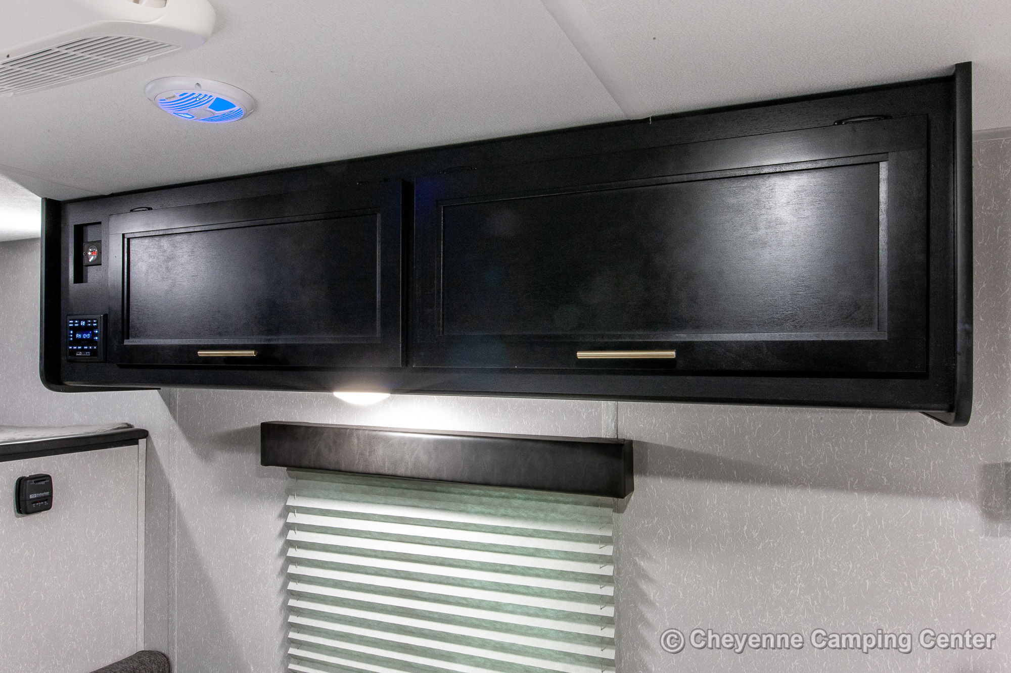 RV rental interior: Sleek dark overhead cabinets, integrated control panel, LED lighting, and window blind for comfort.. Forest River Cherokee Wolf Pup 2021