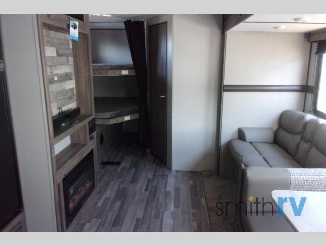 Inside your RV rental: view of living area with sofa, bunk beds, and built-in media console with fireplace.. Crossroads Zinger 2021