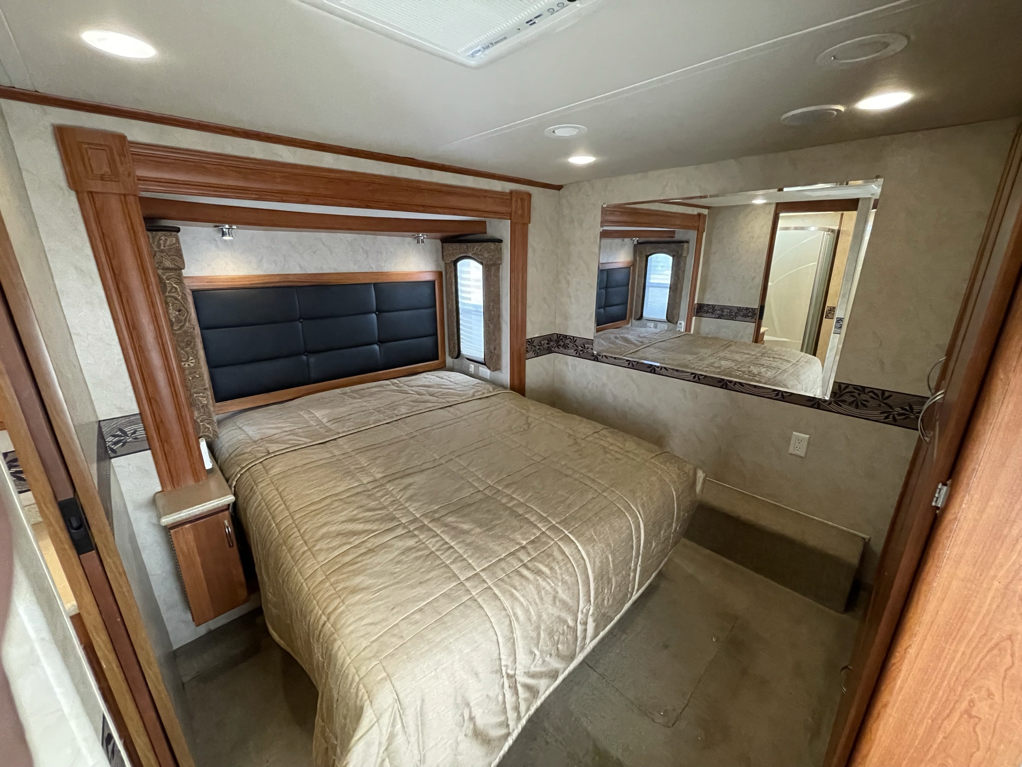 RV rental: Cozy bedroom with a large bed, wood trim, side windows, and reflective mirrors. Ideal for travel.. Monaco La Palma 2009