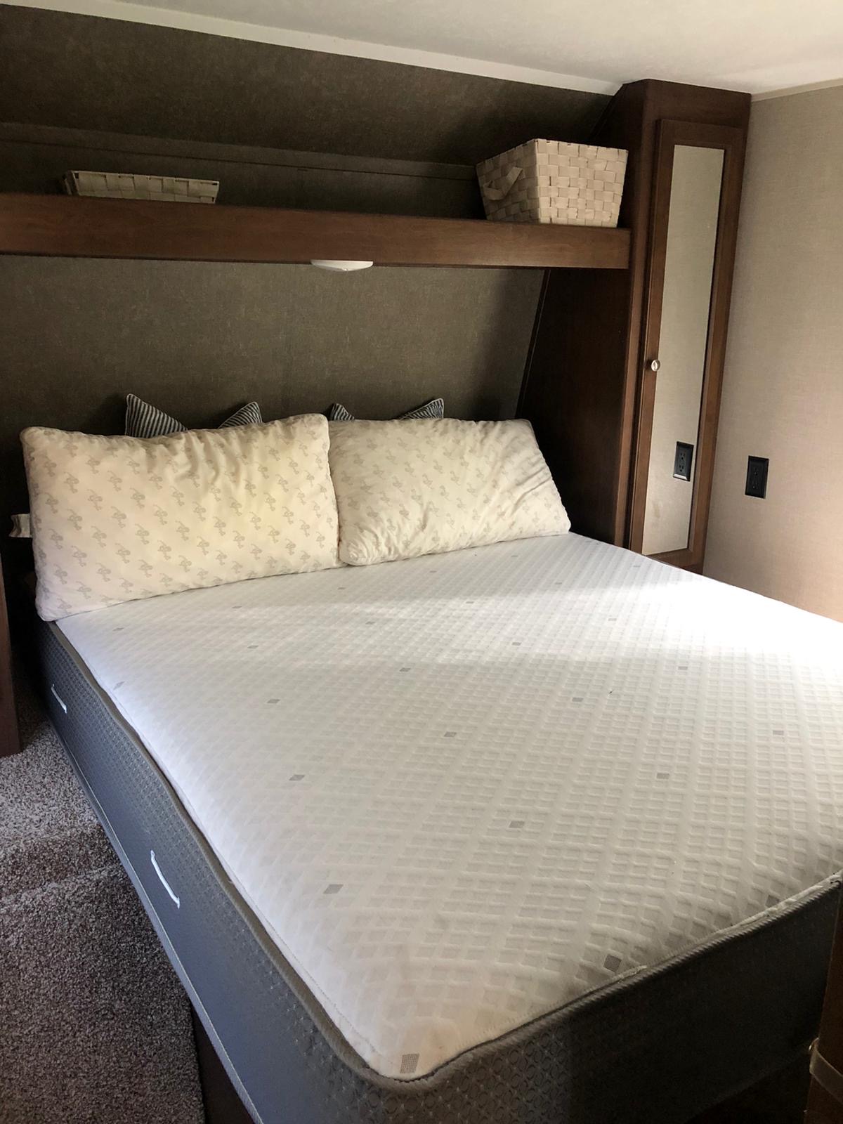 This cozy RV rental bedroom features a comfortable bed, overhead storage, and a mirrored wardrobe.. Keystone Hideout 32 BHTS 2017