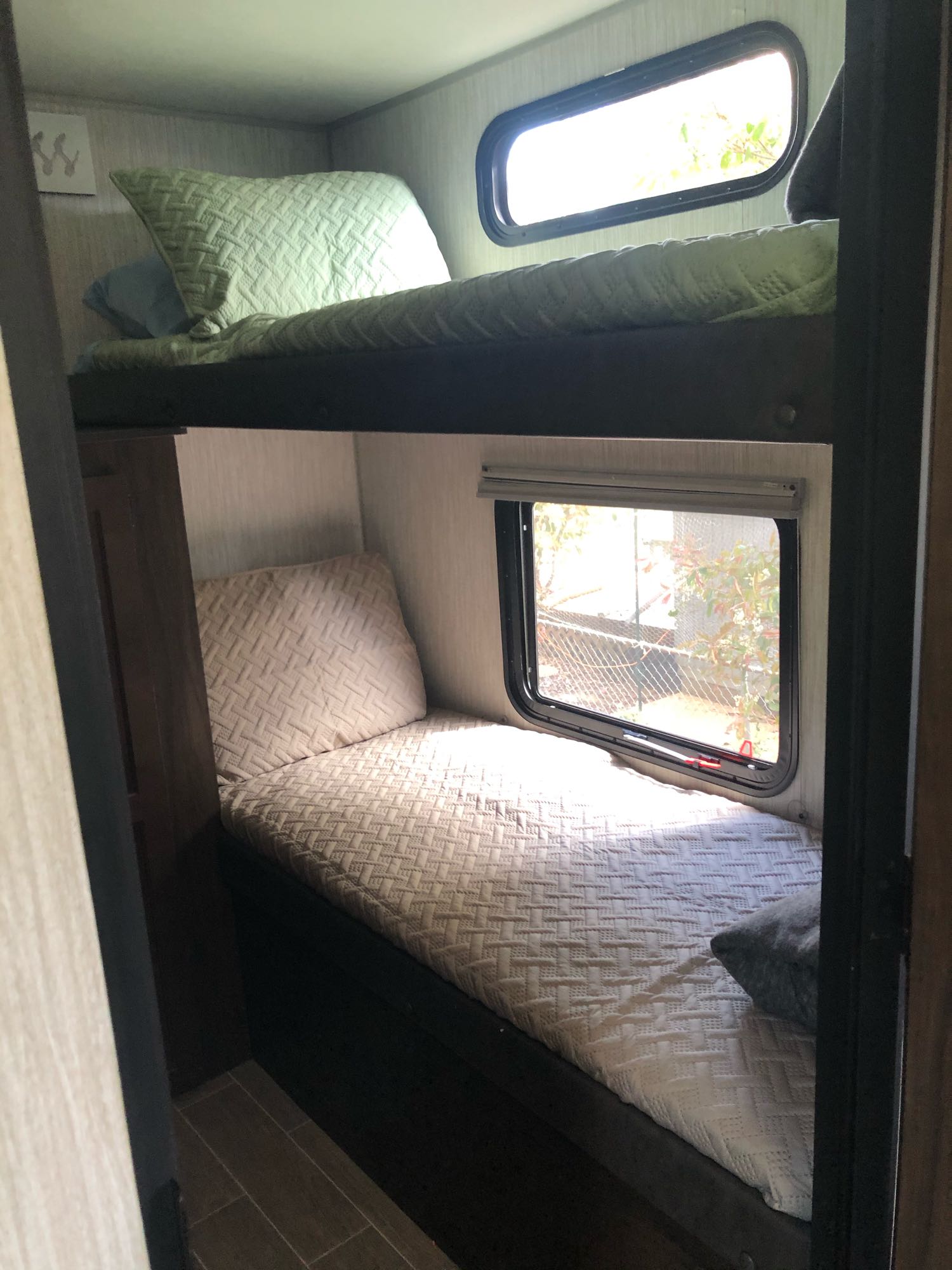 RV rental bunk beds offer comfy sleeping. Top bunk has green bedding & window, bottom has light bedding & window.. Forest River Grey Wolf 29te 2021