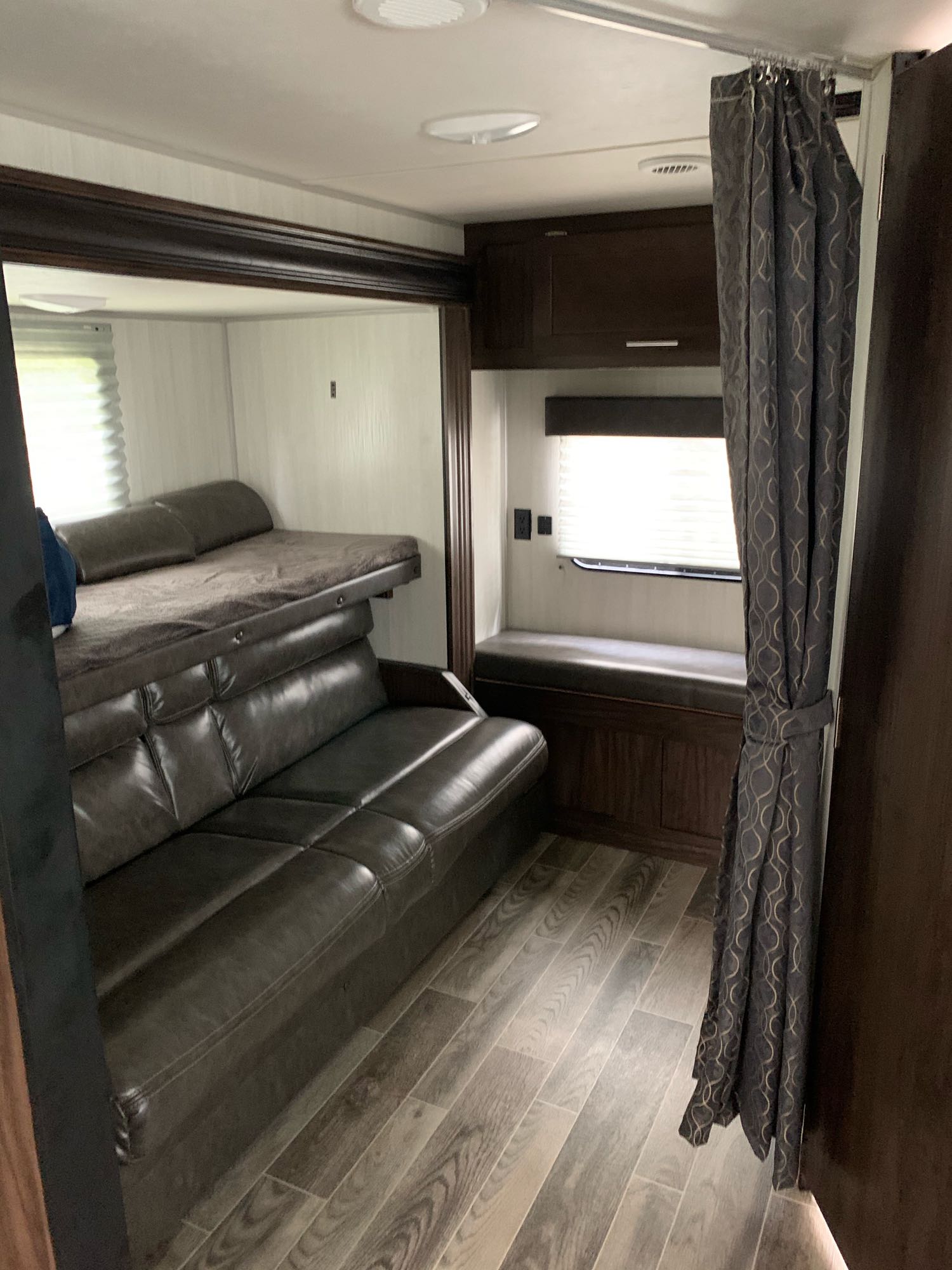 Modern RV rental interior with a bunk bed, convertible sofa, and a cozy window bench.. Forest River Cherokee Grey Wolf 2019