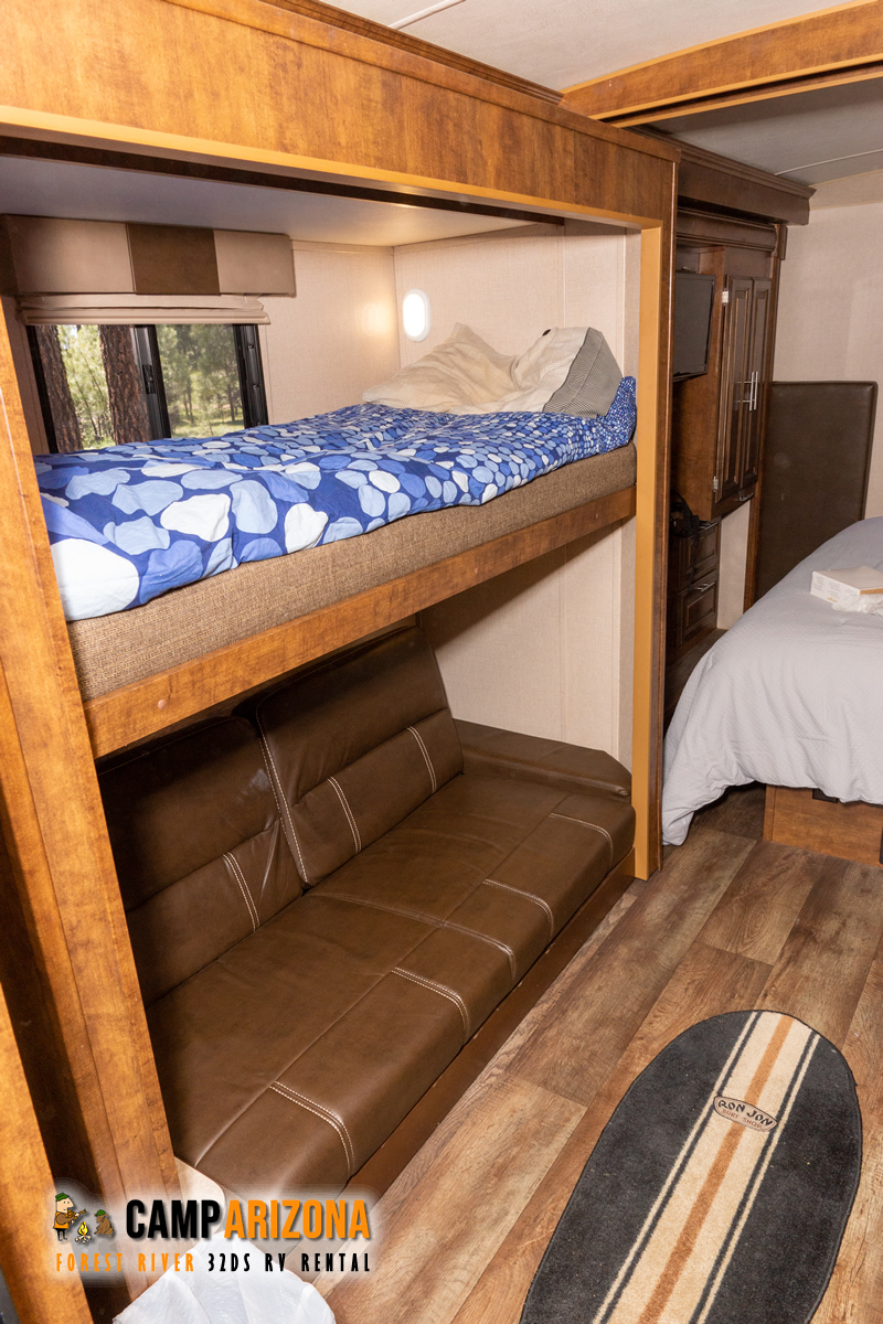 Inside our RV rental: comfy bunk beds, a brown leather-look sofa, and durable wood-style flooring for your trip.. Forest River FR3 32 DS 2016